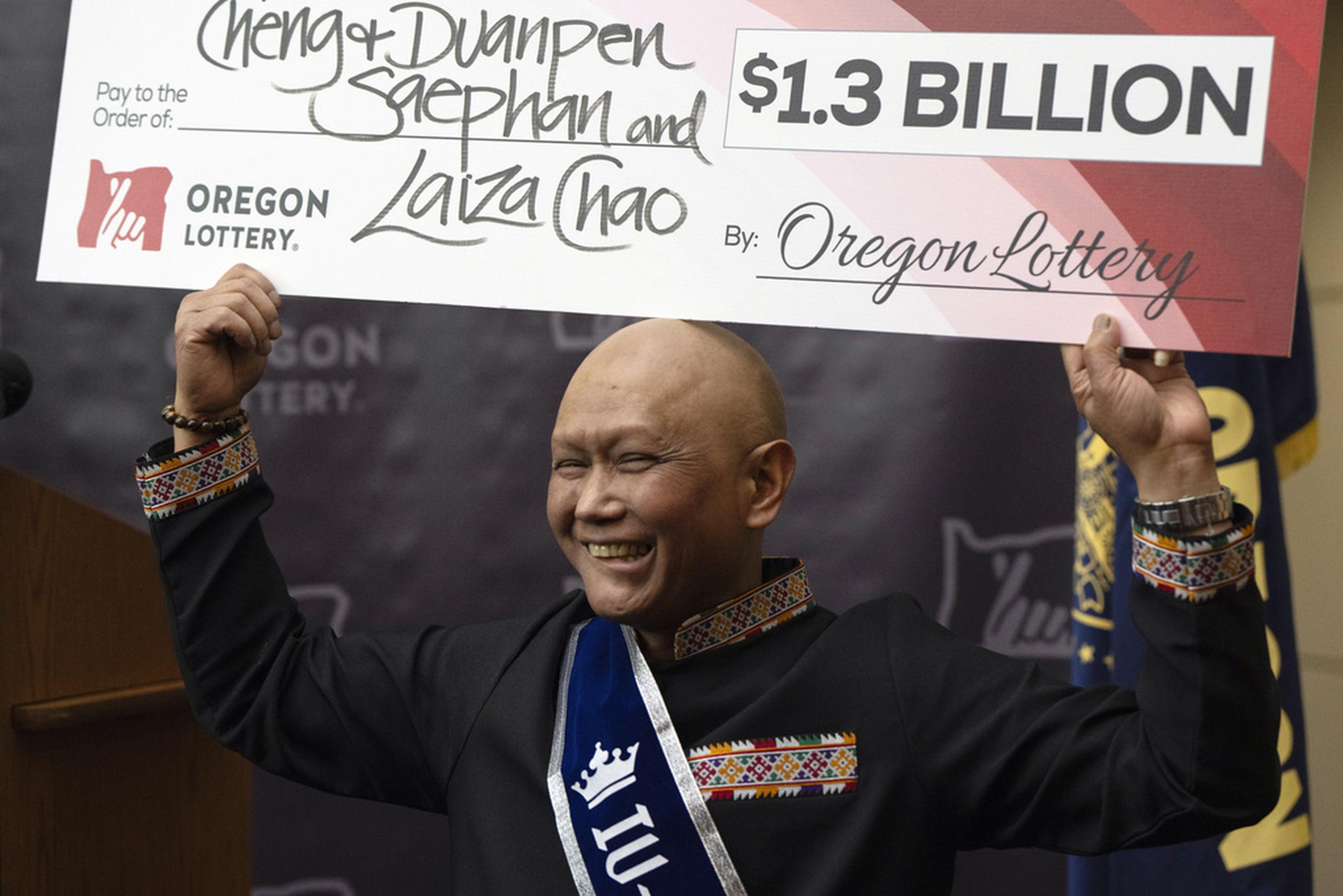 Cheng Saephan levanta un cheque después de hablar en una conferencia de prensa el lunes 29 de abril de 2024 en las oficinas de la Lotería de Oregon, en Salem, Oregon, en la que se reveló que fue uno de los ganadores del premio de 1.300 millones de dólares de la lotería Powerball.