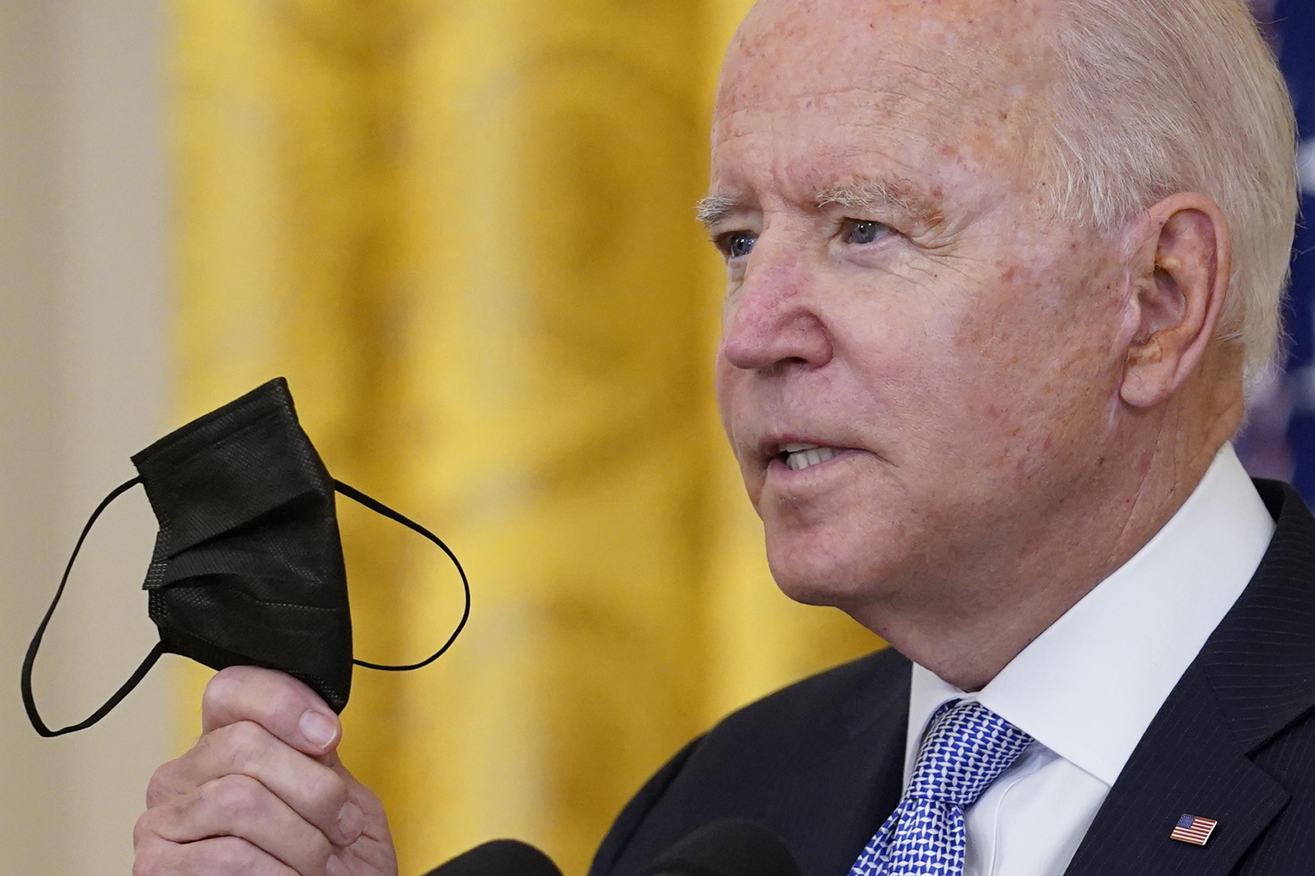 El presidente Joe Biden sostiene una mascarilla mientras habla sobre unas medidas nuevas relacionadas con el coronavirus para los trabajadores federales en la Casa Blanca, en Washington.