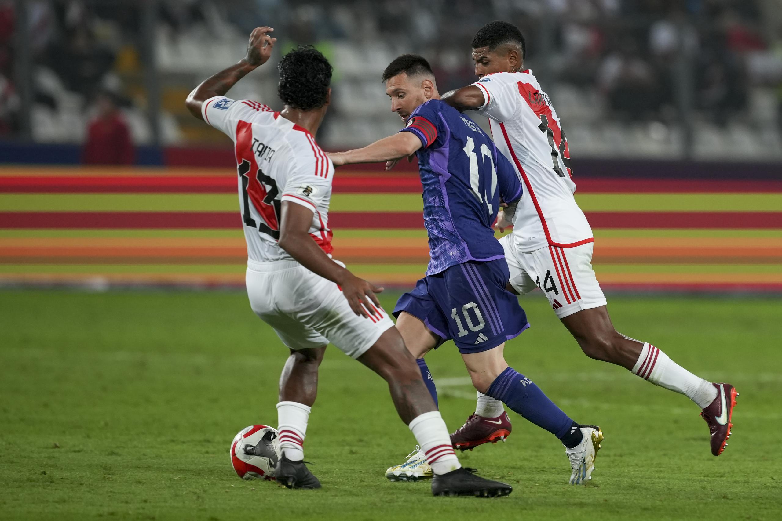 Lionel Messi, de la selección de Argentina, avanza entre Renato Tapia (izquierda) y Wilder Cartagena, de Perú, en un encuentro de la eliminatoria mundialista, el martes 17 de octubre de 2023, en Lima.