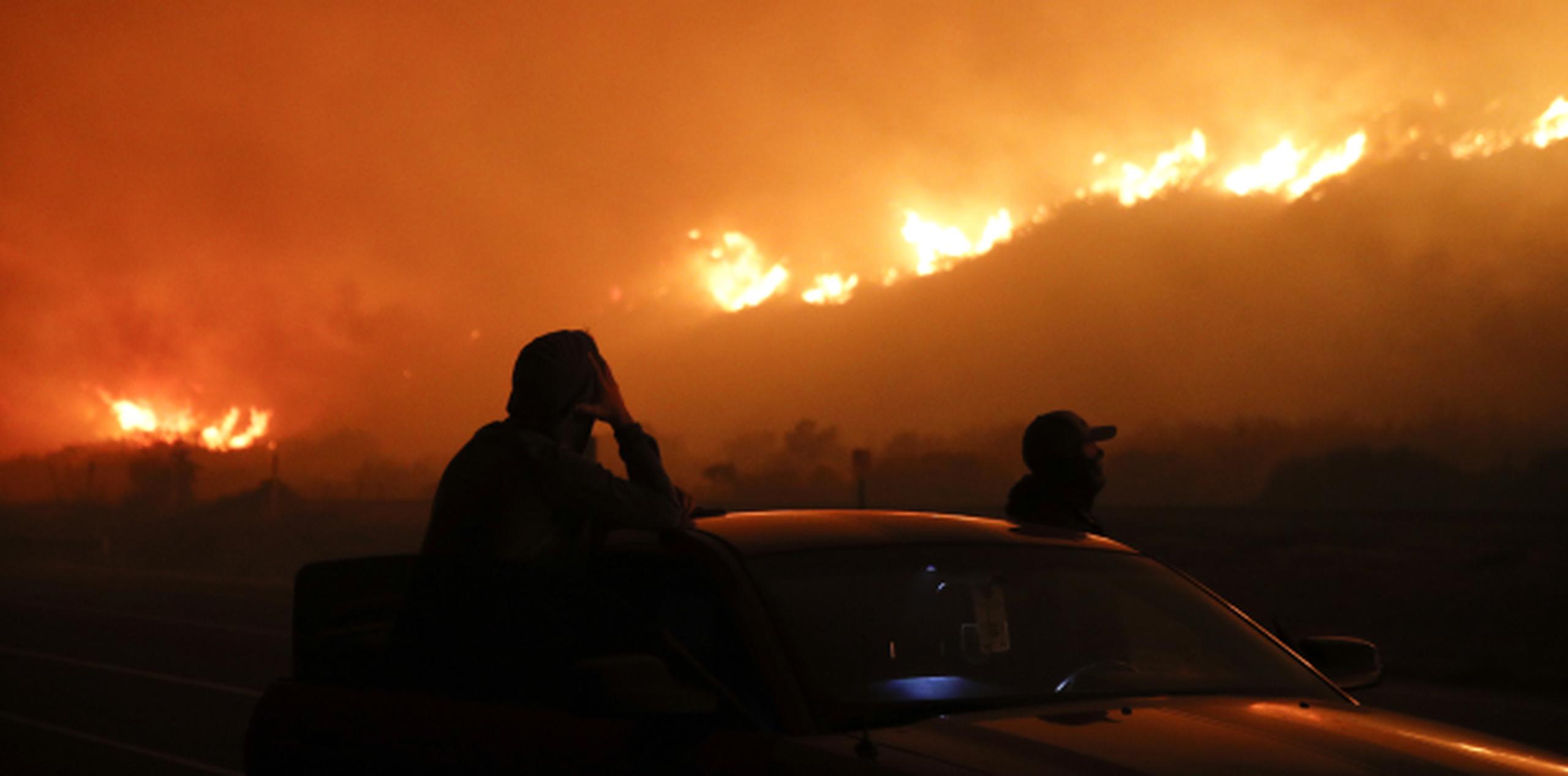 Un par de ciudadanos observa desde una carretera parte de los fuegos en el sector de Ventura, California,. donde destruyó residencias y un hospital. (AP)