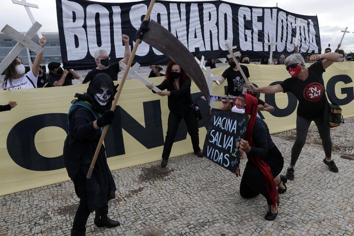 Un manifestante carga un cartel con la frase "Vacunas salvan vidas" (en portugués) mientras otro disfrazado de la muerte lleva una banda presidencial en protesta contra la gestión del presidente Jair Bolsonaro en el exterior del Palacio de Planalto, en Brasilia.
