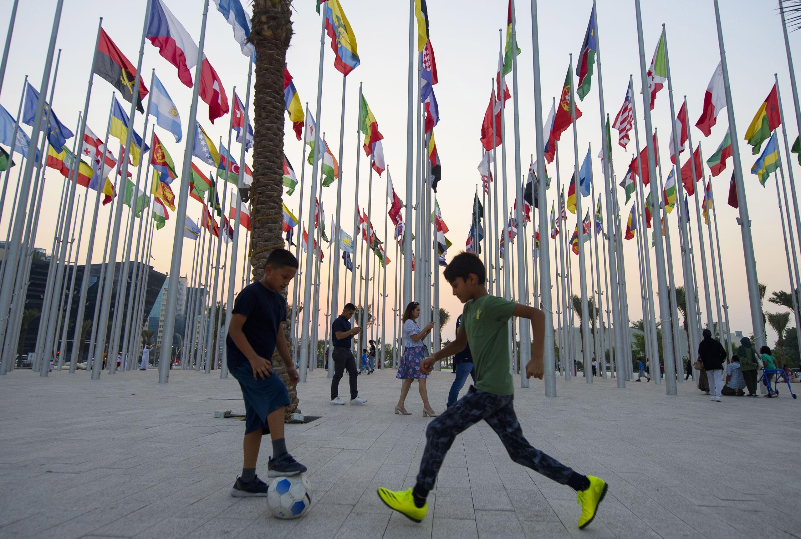 Niños juegan al fútbol en una plaza de Doha, capital de Catar, rodeado de las banderas de las selecciones participantes en el próximo Mundial de fútbol. EFE/EPA/NOUSHAD THEKKAYIL
