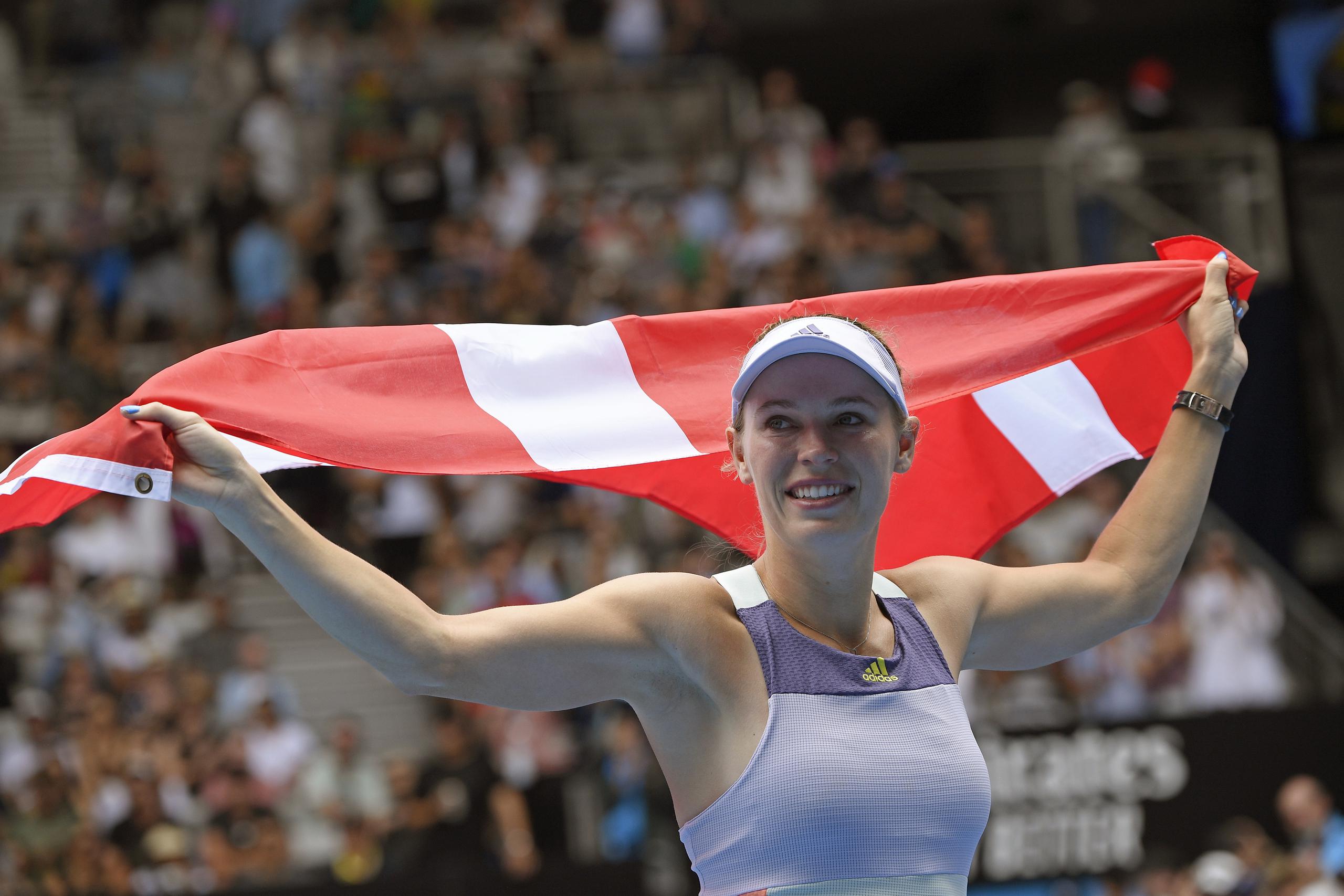 Caroline Wozniacki carga al bandera de Dinamarca al despedirse del público en el Abierto de Australia.