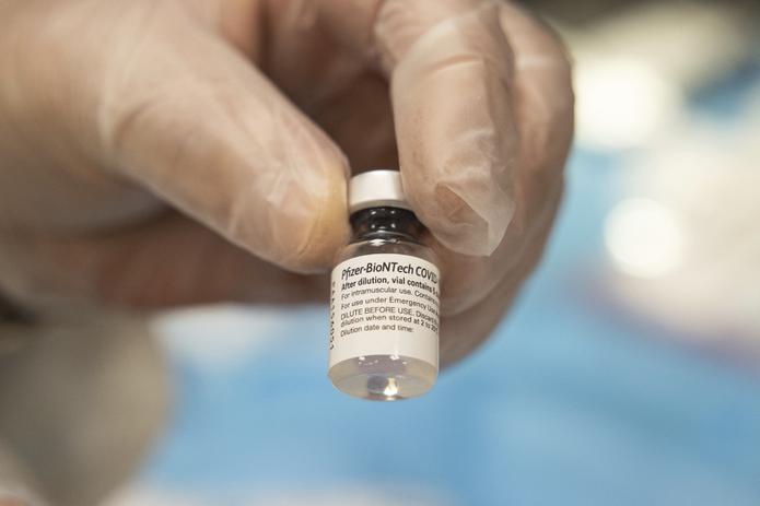 Un empleado de la farmacia CVS muestra el frasco que contiene la vacuna contra el COVID-19 diseñada por Pfizer y BioNTech.
