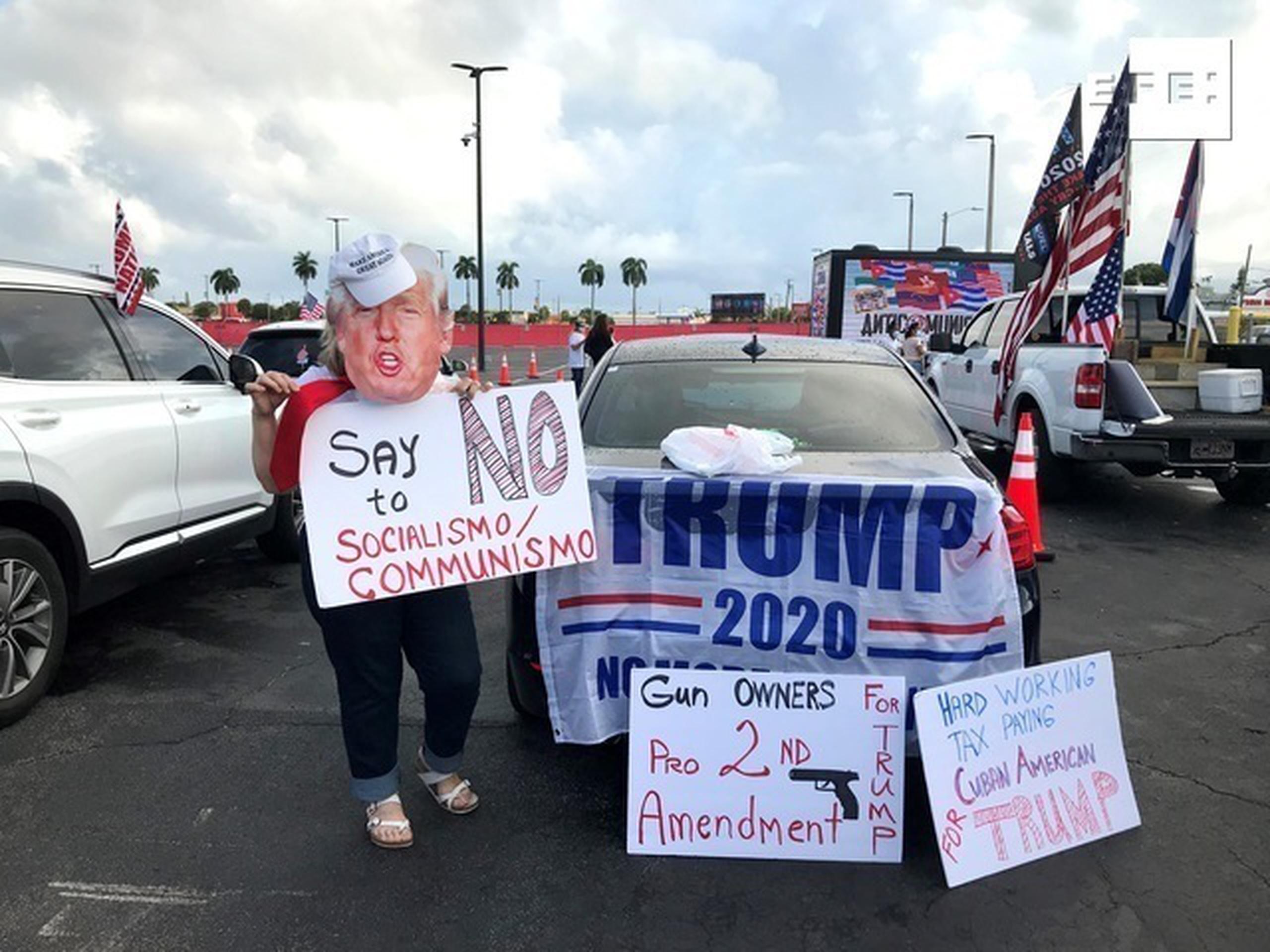 Unas personas sostienen carteles a favor del presidente Donald Trump mientras participan una manifestación multitudinaria contra el comunismo el 10 de octubre de 2020, en Miami, Florida (EEUU).