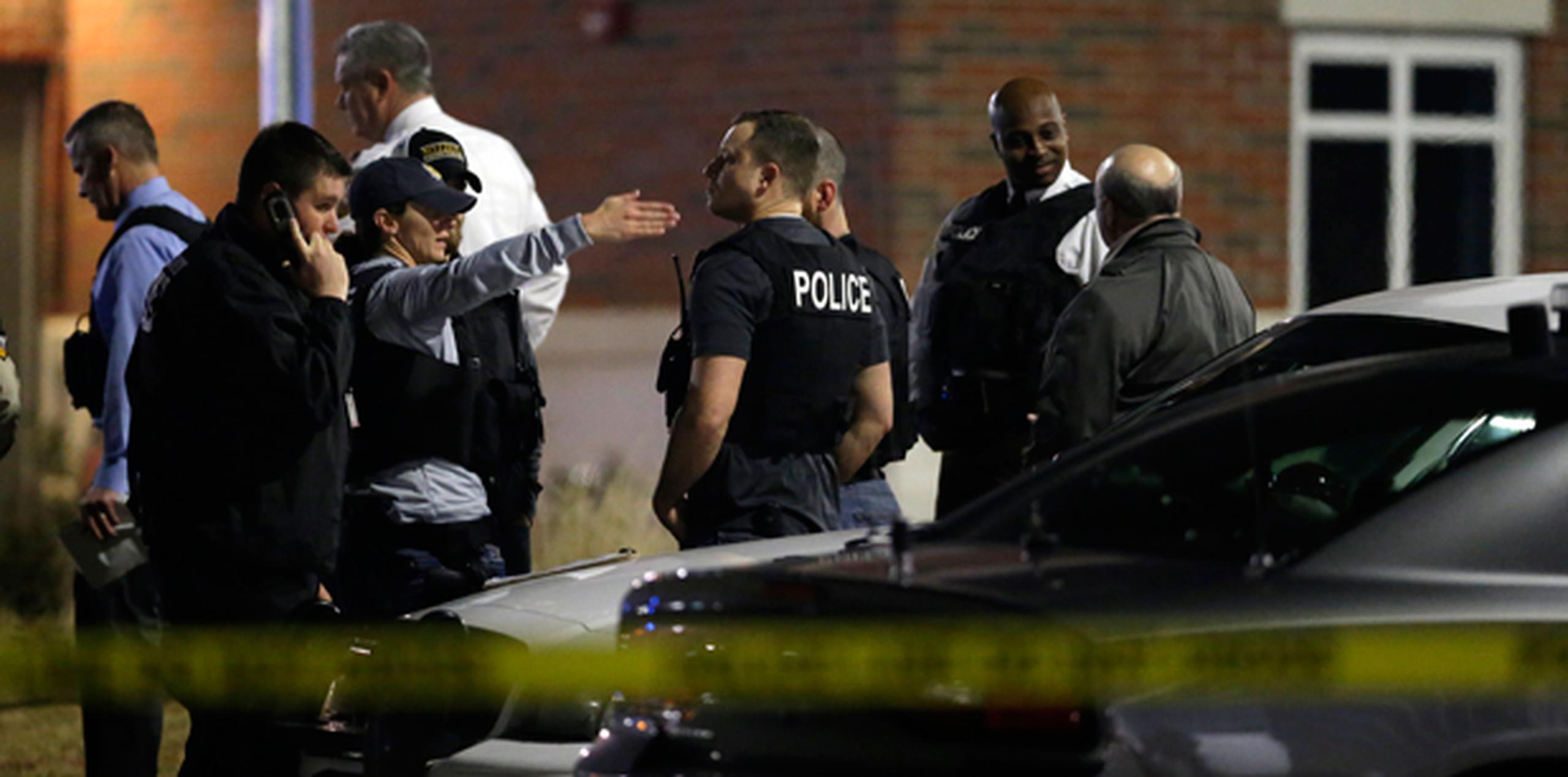 Agentes investigan la escena en la que dos policías fueron tiroteados a las afueras del Departamento de la Policía de Ferguson. (AP)