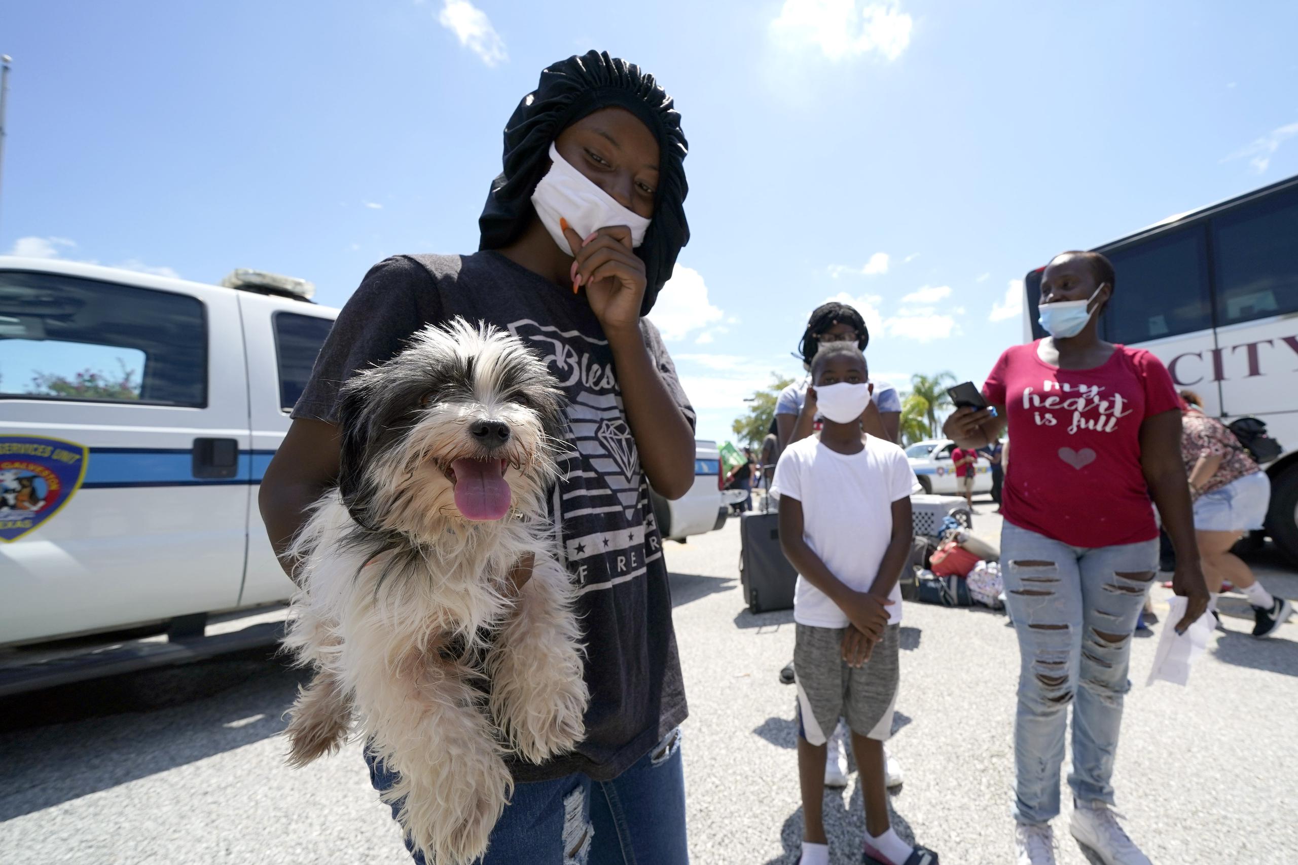 Tiara Walker sostiene a su perro, Buece, mientras espera con su familia para abordar un autobús para evacuar Galveston, Texas.