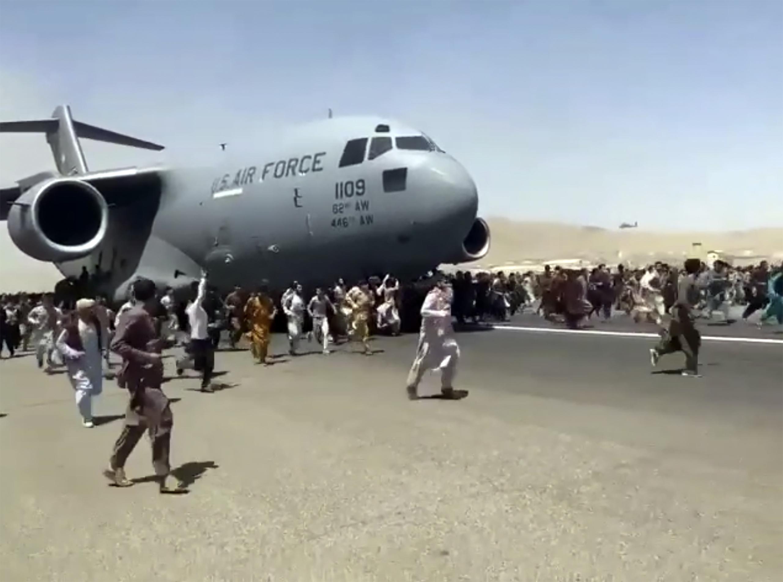 Cientos de personas corren junto a un avión C-17 de las fuerzas armadas de Estados Unidos en el aeropuerto de Kabul en Afganistán.
