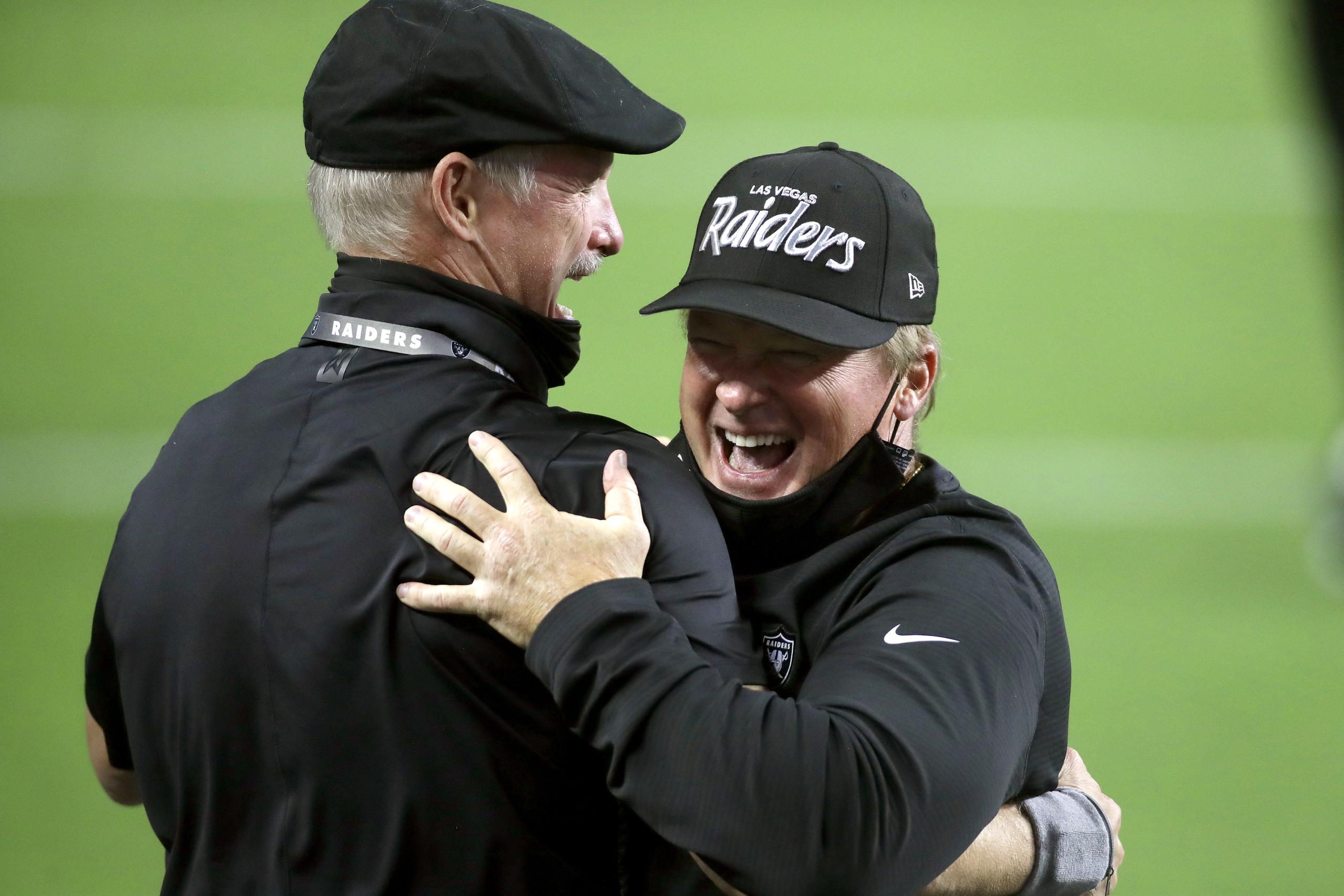 El gerente de los Raiders, Mike Mayock, izquierda, y el dirigente del equipo, Jon Gruden, se abrazan luego de la victoria del lunes sobre Nueva Orleans. Gruden sería multado por violar la regla de uso de la mascarilla.