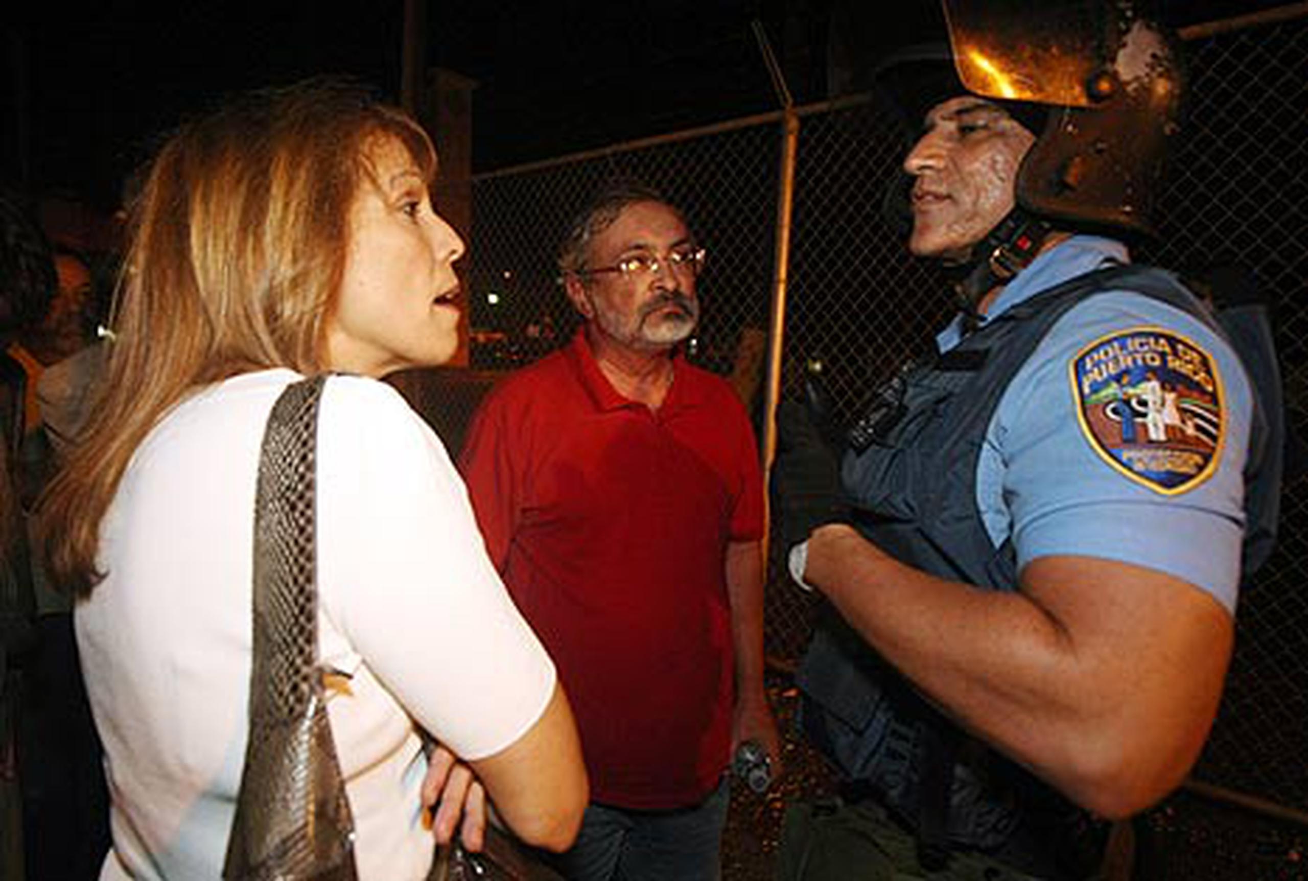 La abogada María de Lourdes Guzmán y el profesor Julio Muriente hablan con un policía frente a la Unidad de Operaciones Tácticas en Puerta de Tierra. (Primera Hora / Juan Luis Martínez)