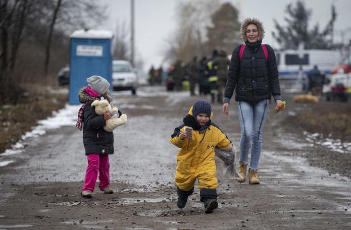 Niños, seguidos por una mujer, corren al llegar al cruce fronterizo en Medyka, Polonia, después de huir de Ucrania, el miércoles 9 de marzo de 2022.