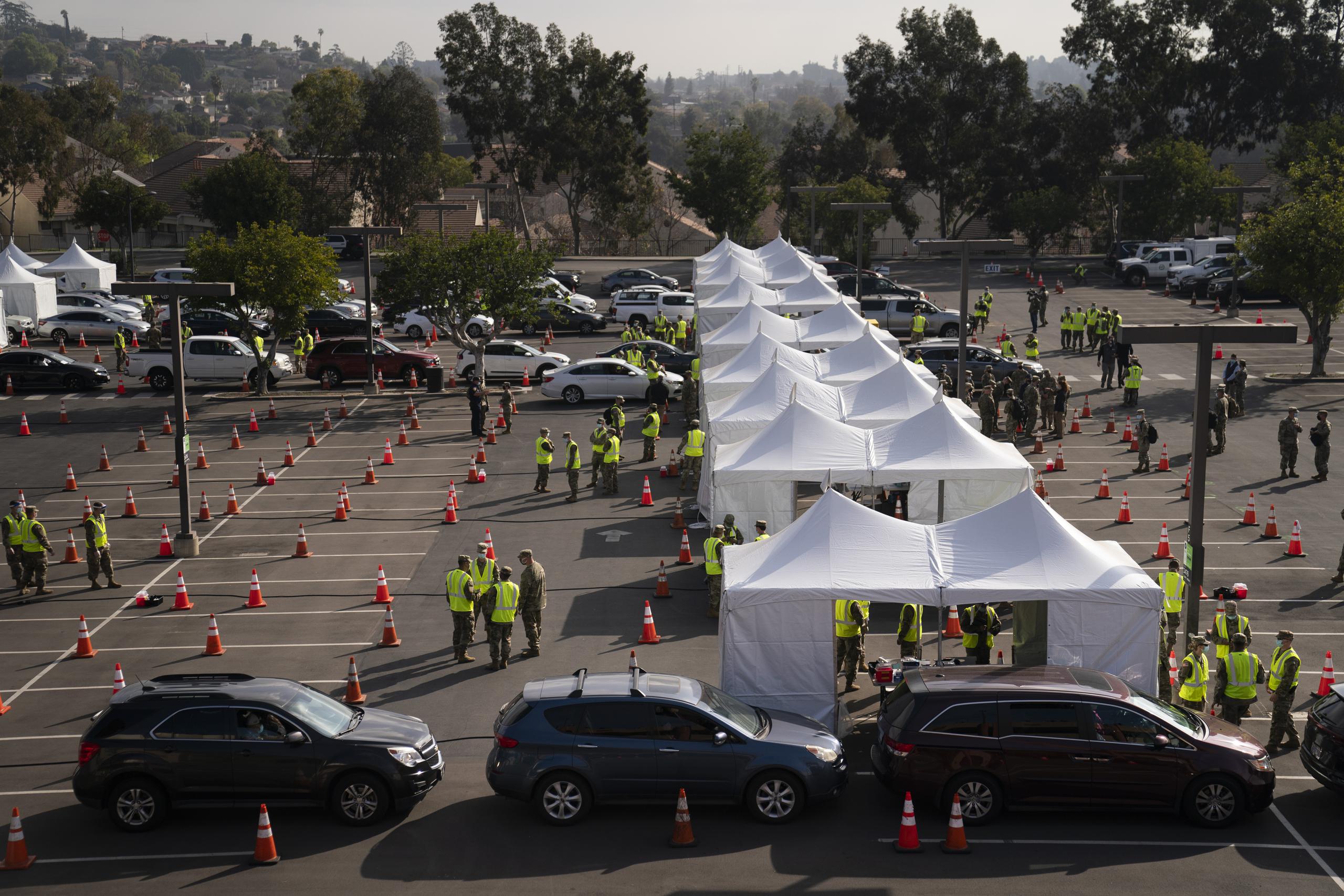 Personas en sus automóviles llegan a vacunarse contra el COVID-19 en un sitio masivo administrado por el gobierno federal, en el campus de la Universidad Estatal de California en Los Ángeles.