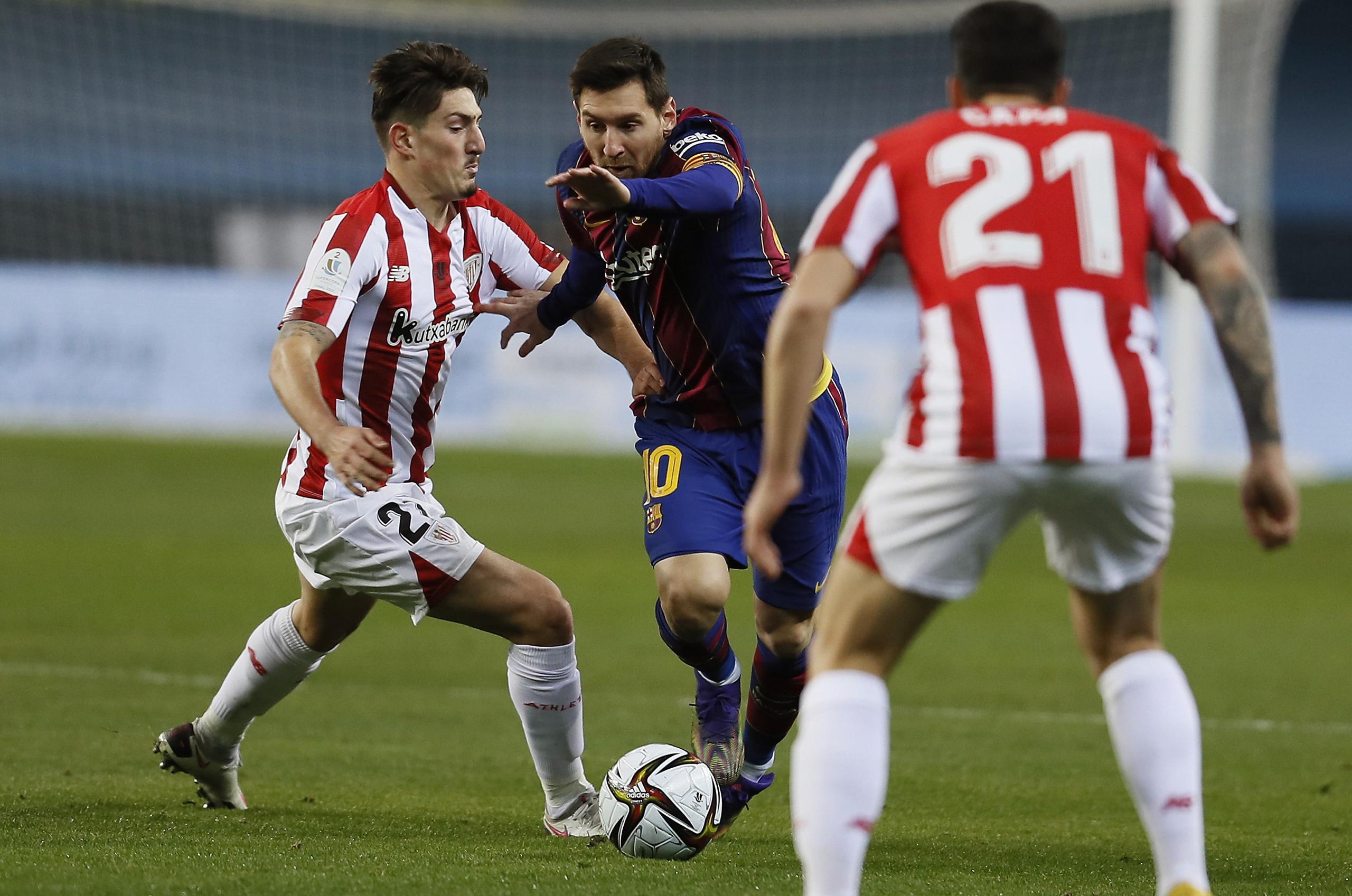 El delantero argentino del FC Barcelona, Leo Messi, al centro, intenta llevarse el balón ante el centrocampista del Ahtletic, Unai Vencedor, durante el encuentro del domingo en la final de la Supercopa de España.