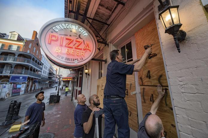 En una escena que se repetía en toda la ciudad, empleados de un establecimiento de comida protegían con paneles de madera las ventanas del negocio en Bourbon Street, en el barrio francés, antes de la llegada de Ida.