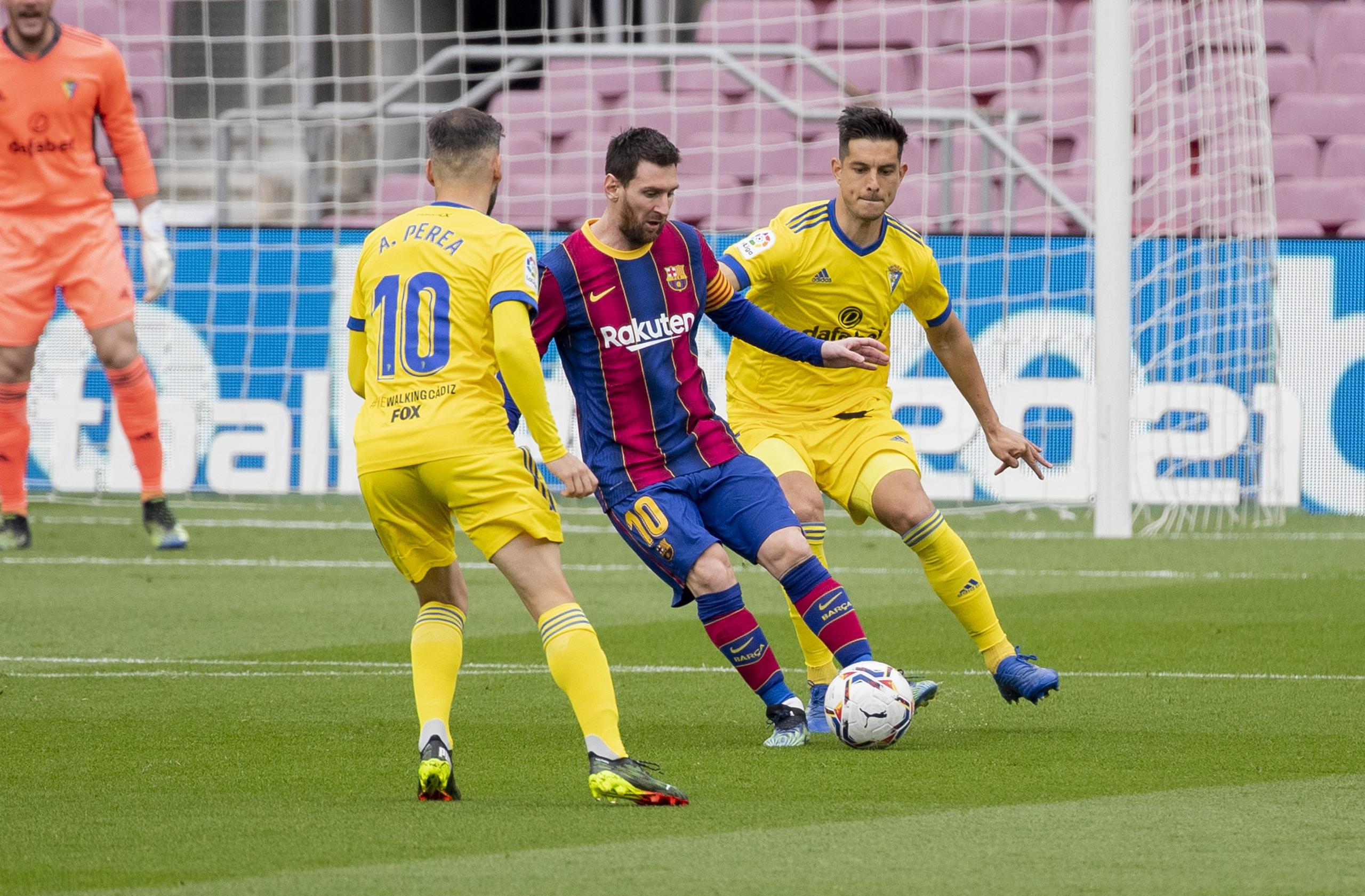 Lionel Messi (centro) controla el balón con Marcos Mauro, de Cádiz, durante el partido de fútbol de la Liga española entre FC Barcelona y Cádiz.