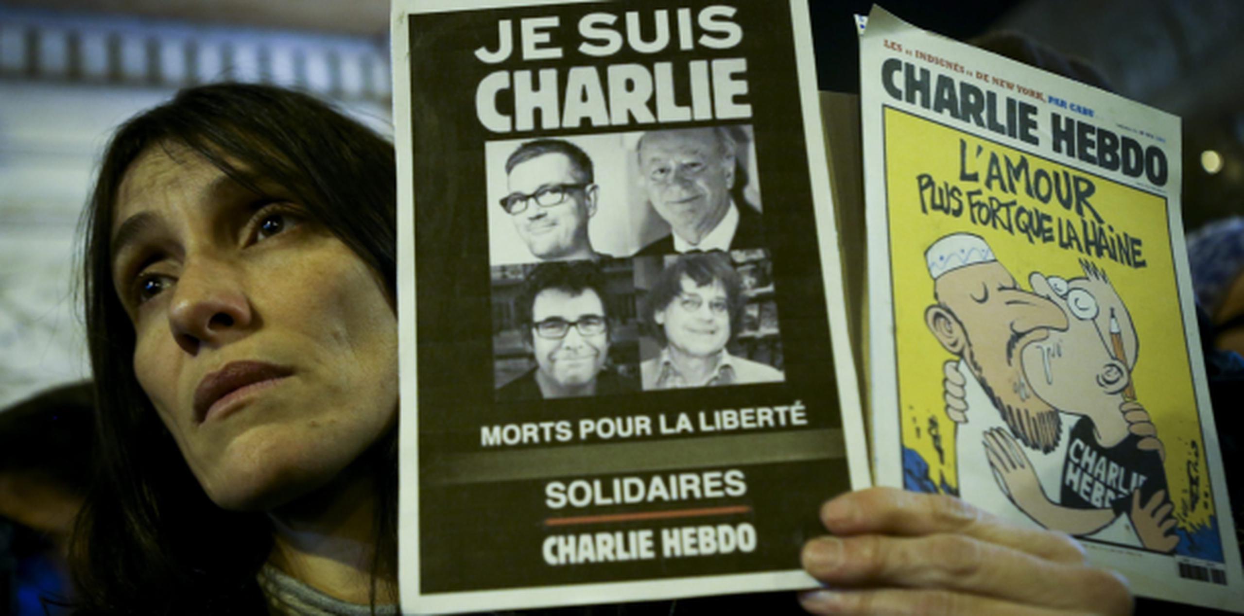 El presidente Francois Hollande hizo un llamado a la tolerancia luego del ataque terrorista más grave en el país en varias décadas. En la foto, una mujer sostiene carteles en los que se lee "Je Suis Charlie' (Yo soy Charlie) y una caricatura. (EFE)