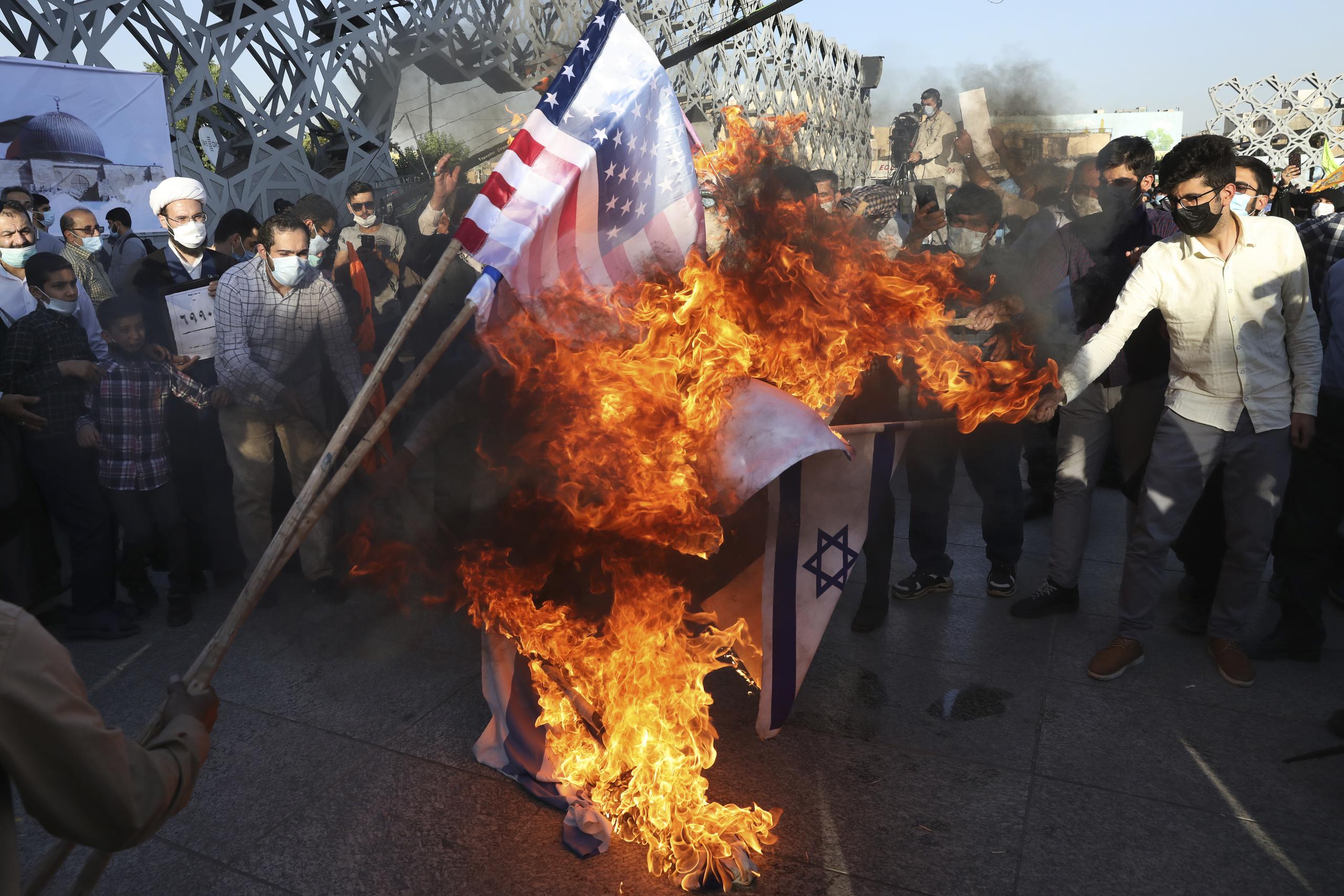 Los manifestantes queman banderas de Estados Unidos e Israel en su reunión pro palestina en Teherán, Irán.