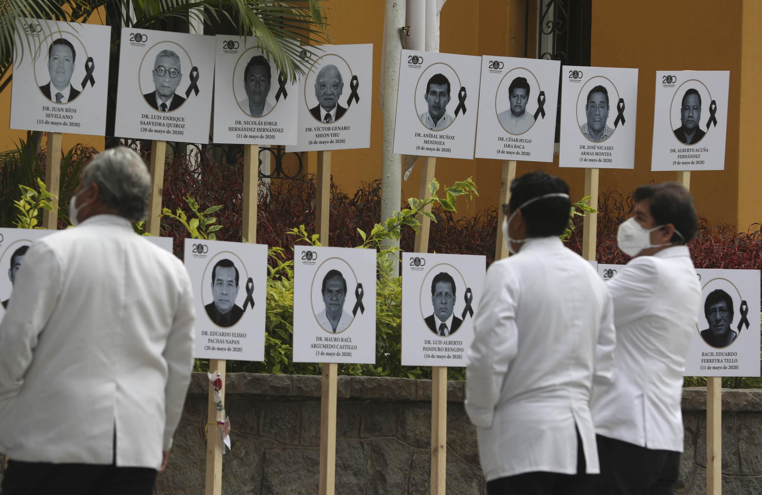 Médicos miran fotos de sus colegas, que murieron de COVID-19 tras atender a pacientes con el virus durante la pandemia en Lima, Perú. (AP)