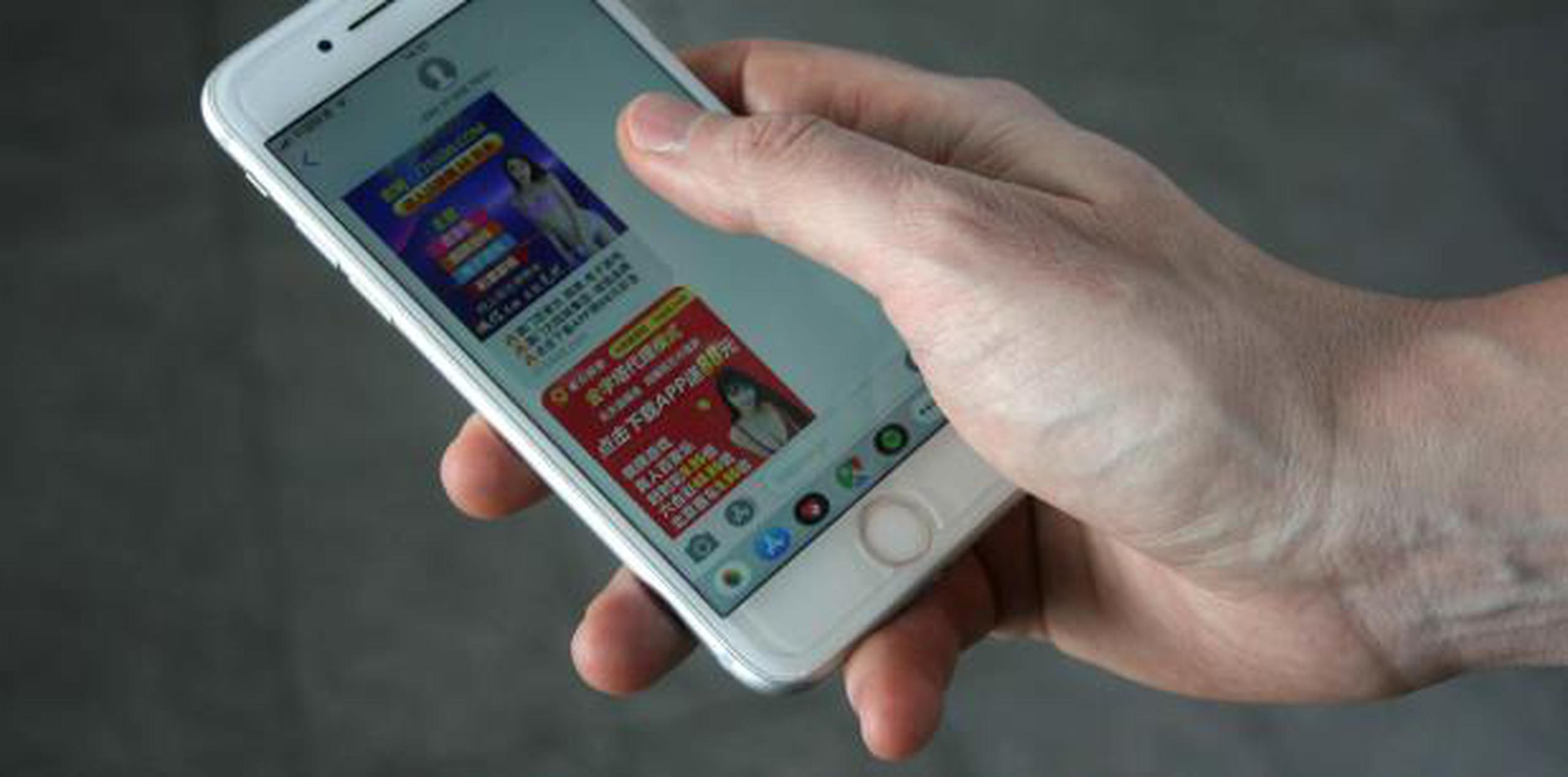 Una persona muestra su teléfono móvil con publicidad erótica, en Pekín, China. (EFE)