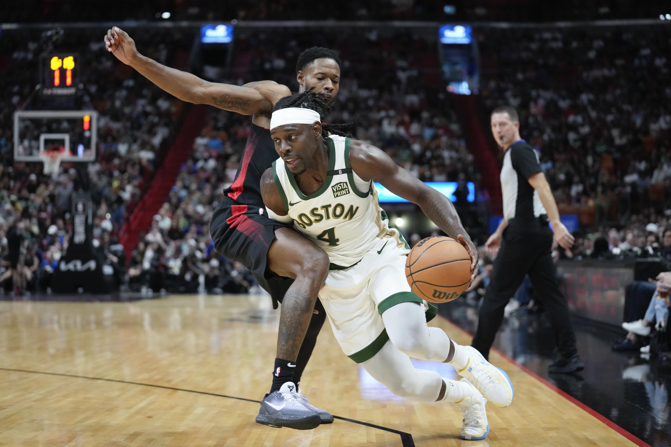 El base de los Celtics de Boston Jrue Holiday avanza hacia la canasta superando al alero del Heat de Miami Haywood Highsmith en el encuentro de la NBA del domingo.