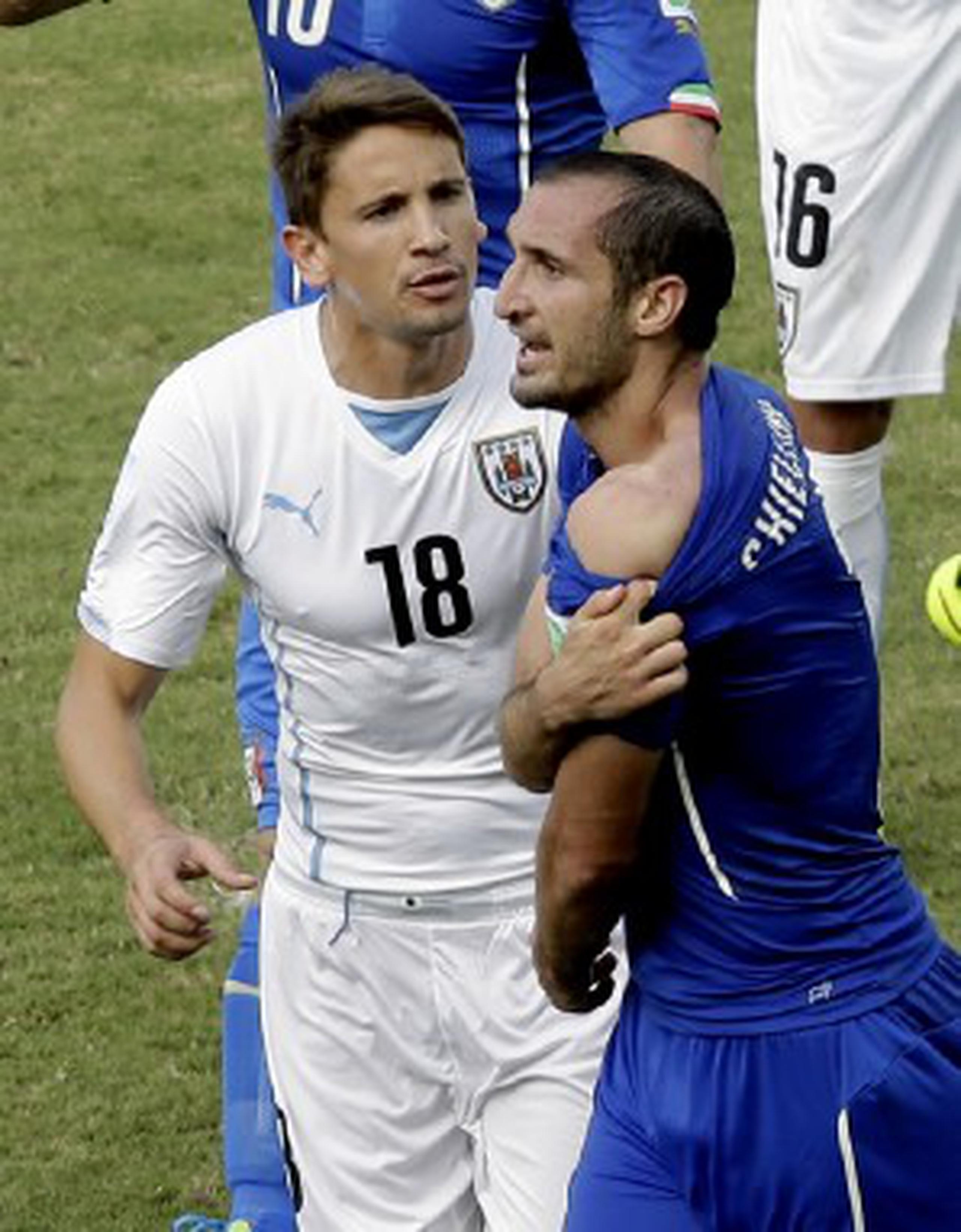 El defensor italiano Giorgio Chiellini muestra la supuesta mordida que recibió en el hombro de parte del uruguayo Luis Suárez. (AP \ Hassan Ammar)