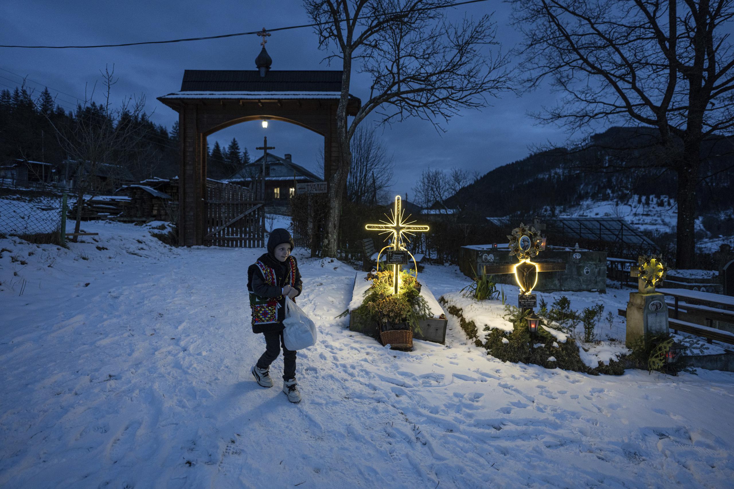 Un niño camina por un cementerio después de una misa por Navidad en Kryvorivnia, Ucrania. (AP Foto/Evgeniy Maloletka)