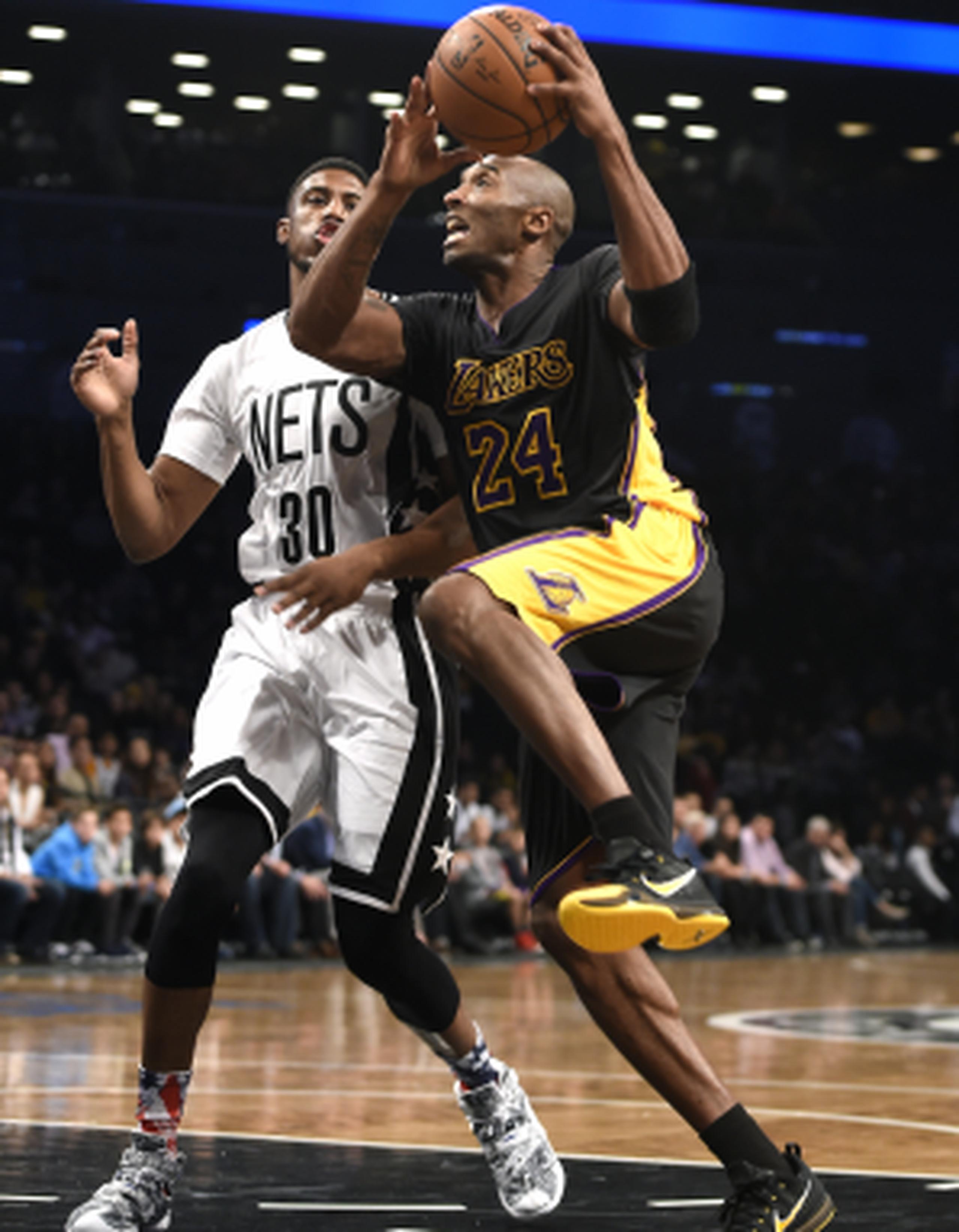 Kobe Bryant, con el balón, intenta anotar ante la presión defensiva de Thaddeus Young, de los Nets. (AP Photo/Kathy Kmonicek)