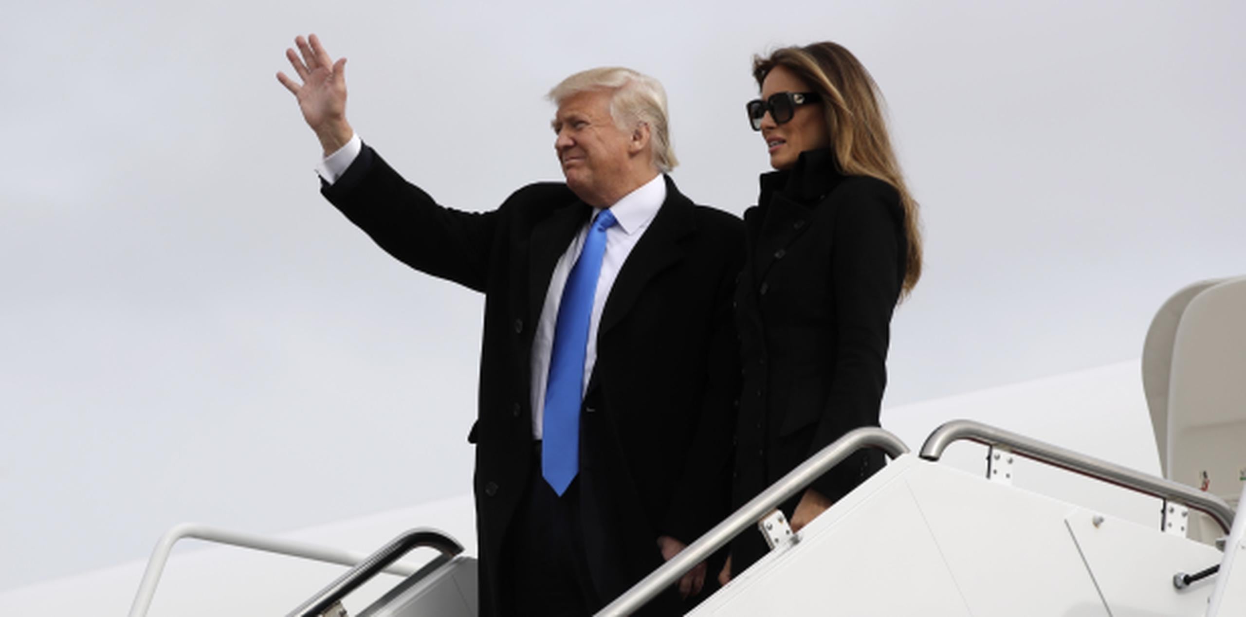 Acompañado de su esposa Melania, el presidente electo saluda tras salir del avión militar que lo llevó hoy a Washington D.C. (AP)
