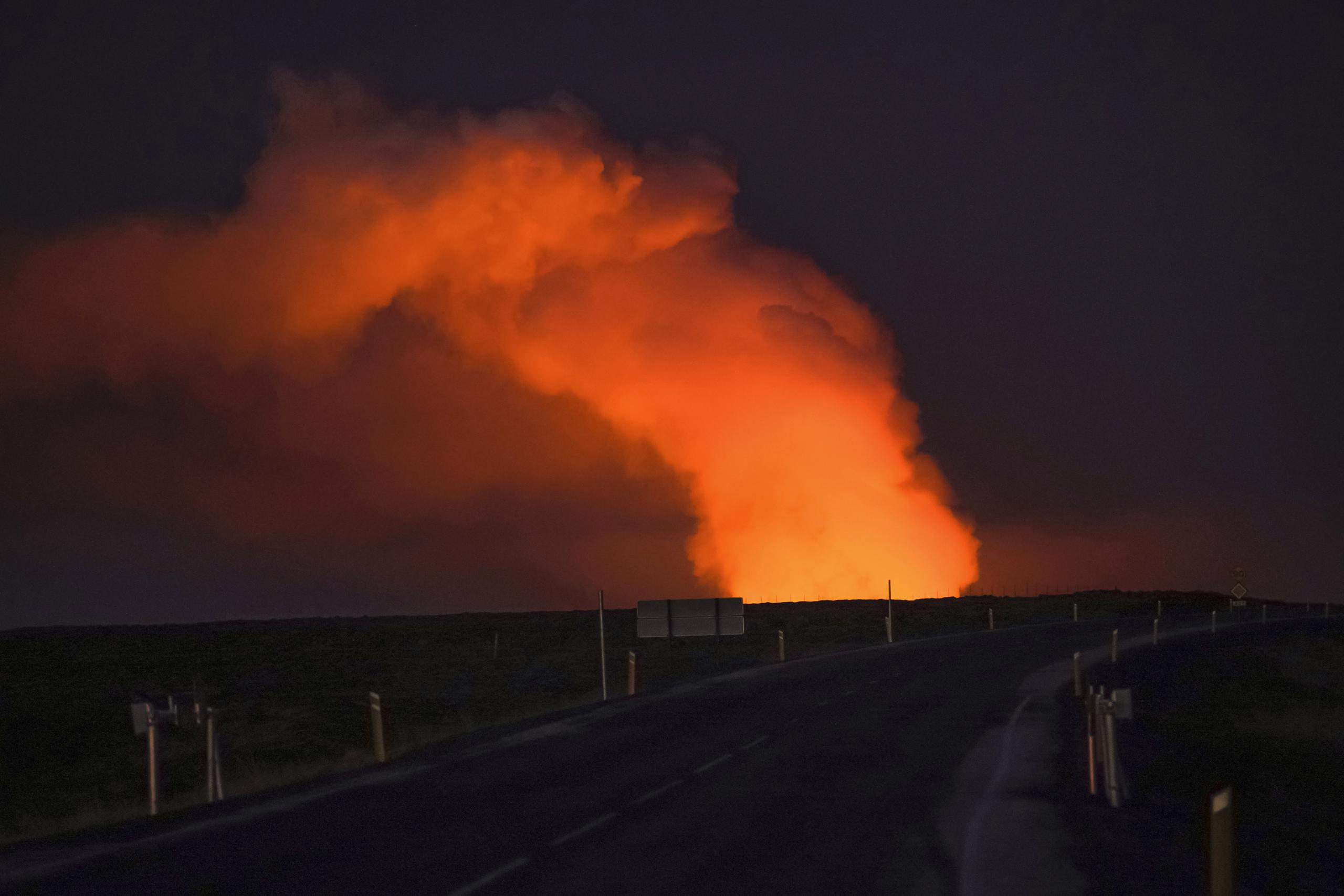 Una columna de gas iluminada por la lava de un volcán en erupción vista desde Suðurstrandavegur, la carretera que lleva a Grindavík, Islandia, el domingo 14 de enero de 2024. (AP Foto/ Marco Di Marco)