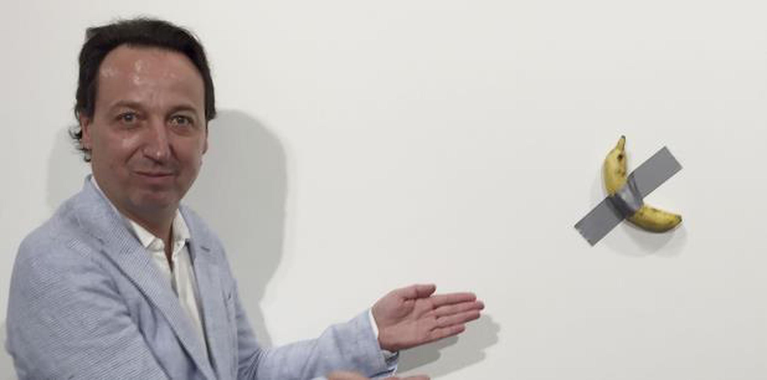 El dueño de la galería Emmanuel Perrotin posa junto a la obra "Comedian" del artista italiano Maurizio Cattlelan durante su exhibición en la feria Art Basel Miami. (Siobhan Morrissey vía AP)