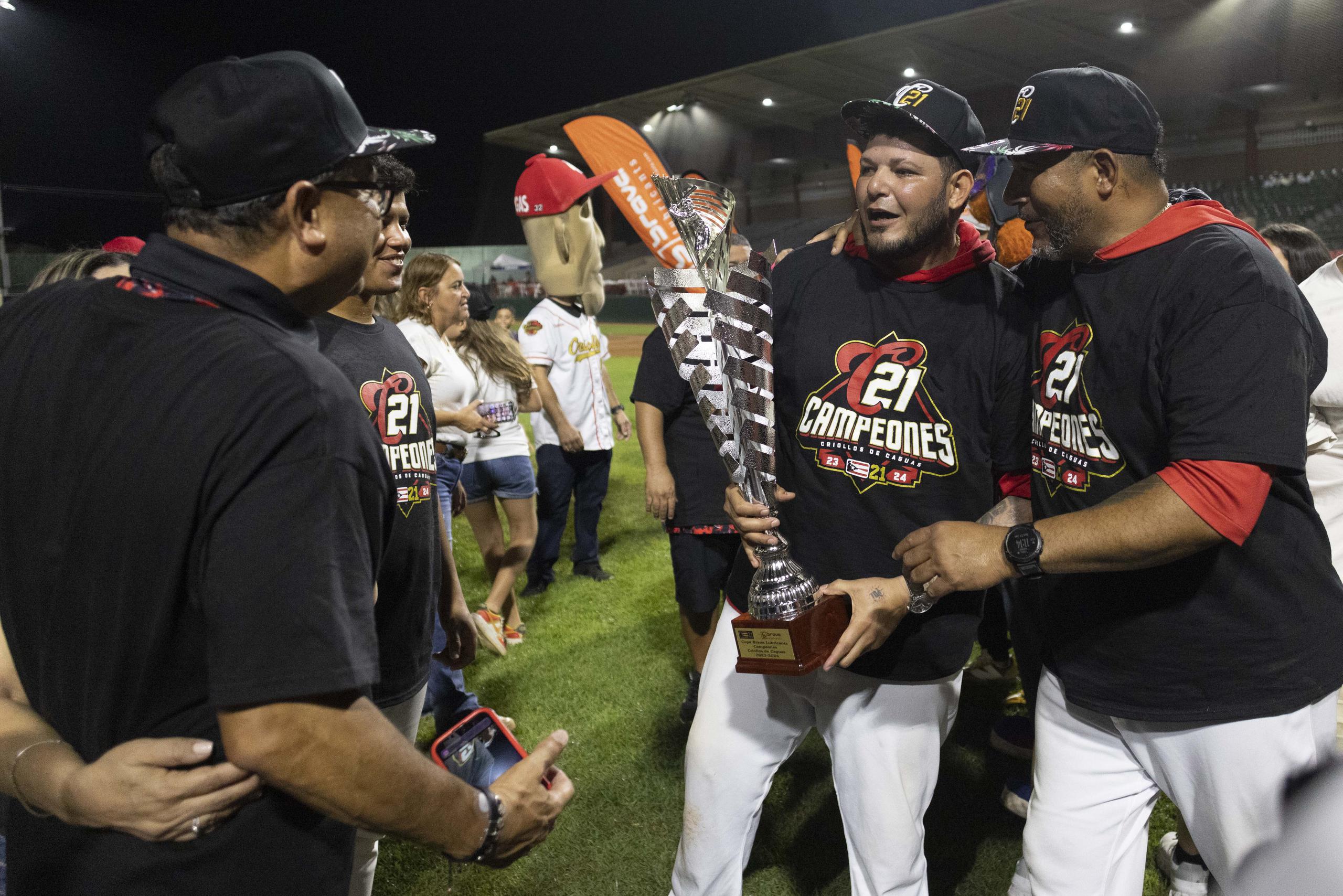 Yadier Molina carga el trofeo de campeones de los Criollos de Caguas junto a su hermano y coach de los Criollos, José 'Cheo' Molina.