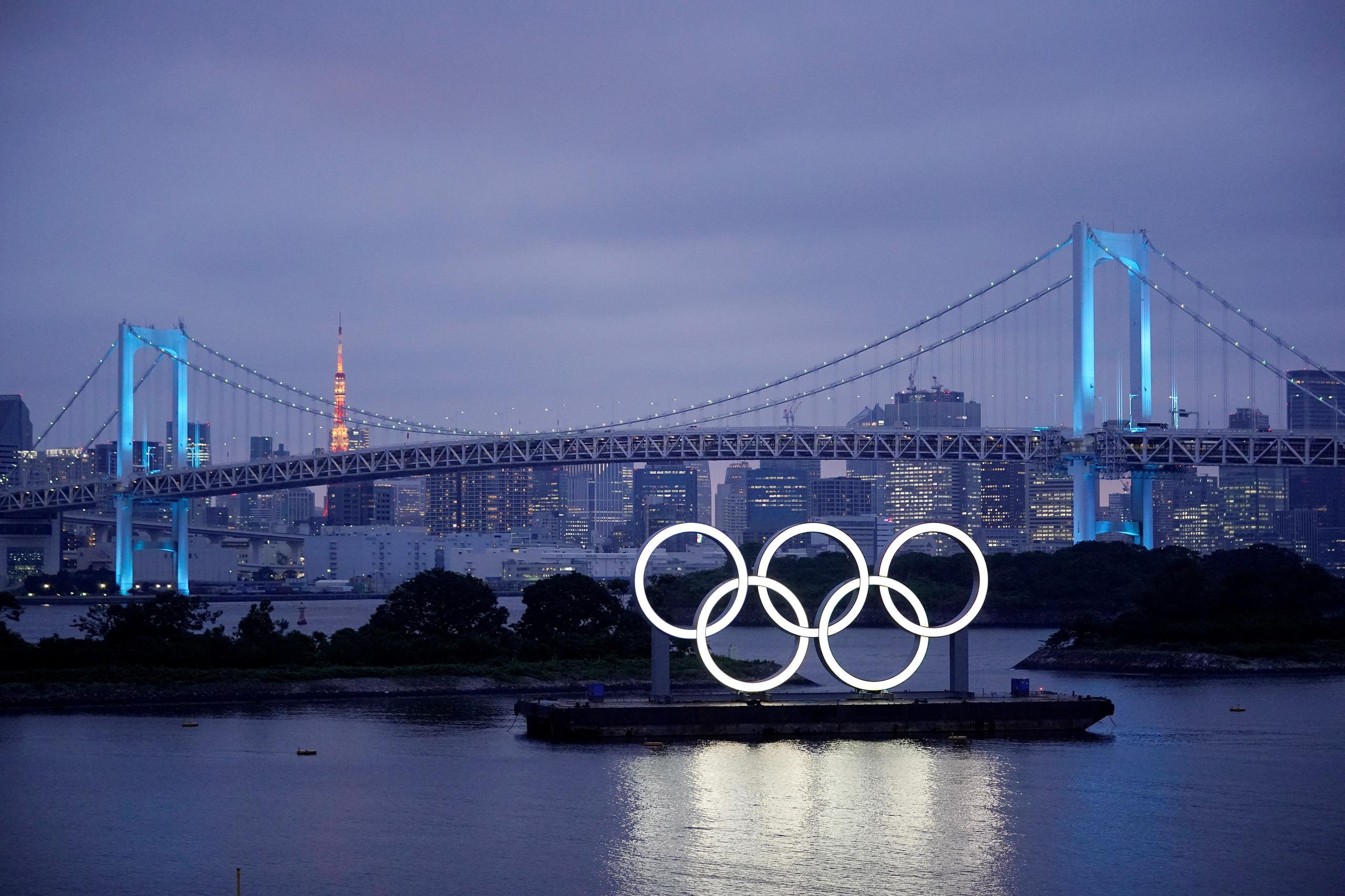 Los aros olímpicos iluminan el agua cerca del Puente del Arco Iris en el Parque Marino de Odaiba, Japón.