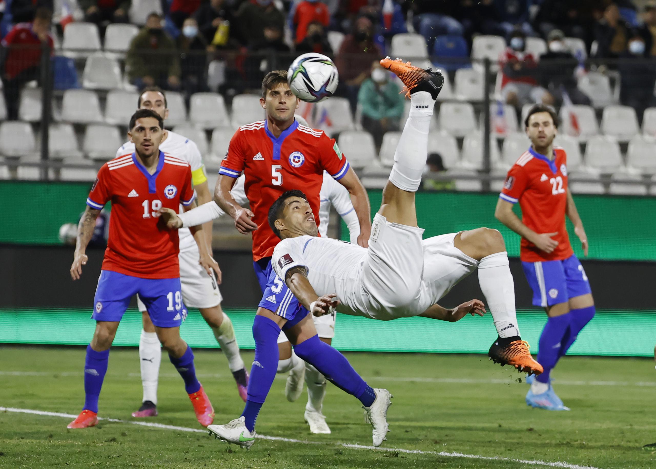 El delantero uruguayo Luis Suárez (centro) define de chilena para anotar el primer gol en la victoria 2-0 ante Chile en las eliminatorias del Mundial, el martes 29 de marzo de 2022, en Santiago. (Alberto Valdés/Pool vía AP)