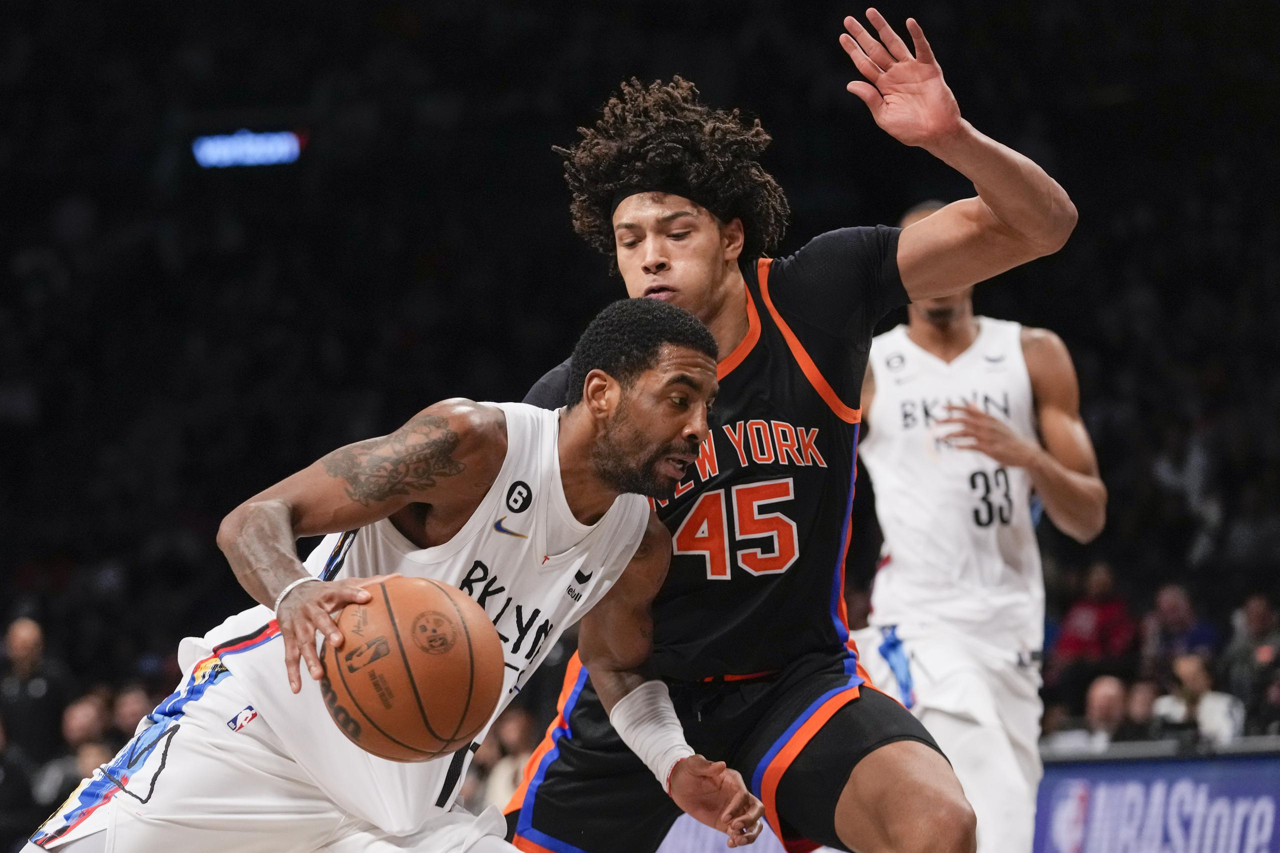El armador de los Nets de Brooklyn, Kyrie Irving, inicia movimientos contra el centro de los Knicks, Jericho Sims durante el partido sabatino.