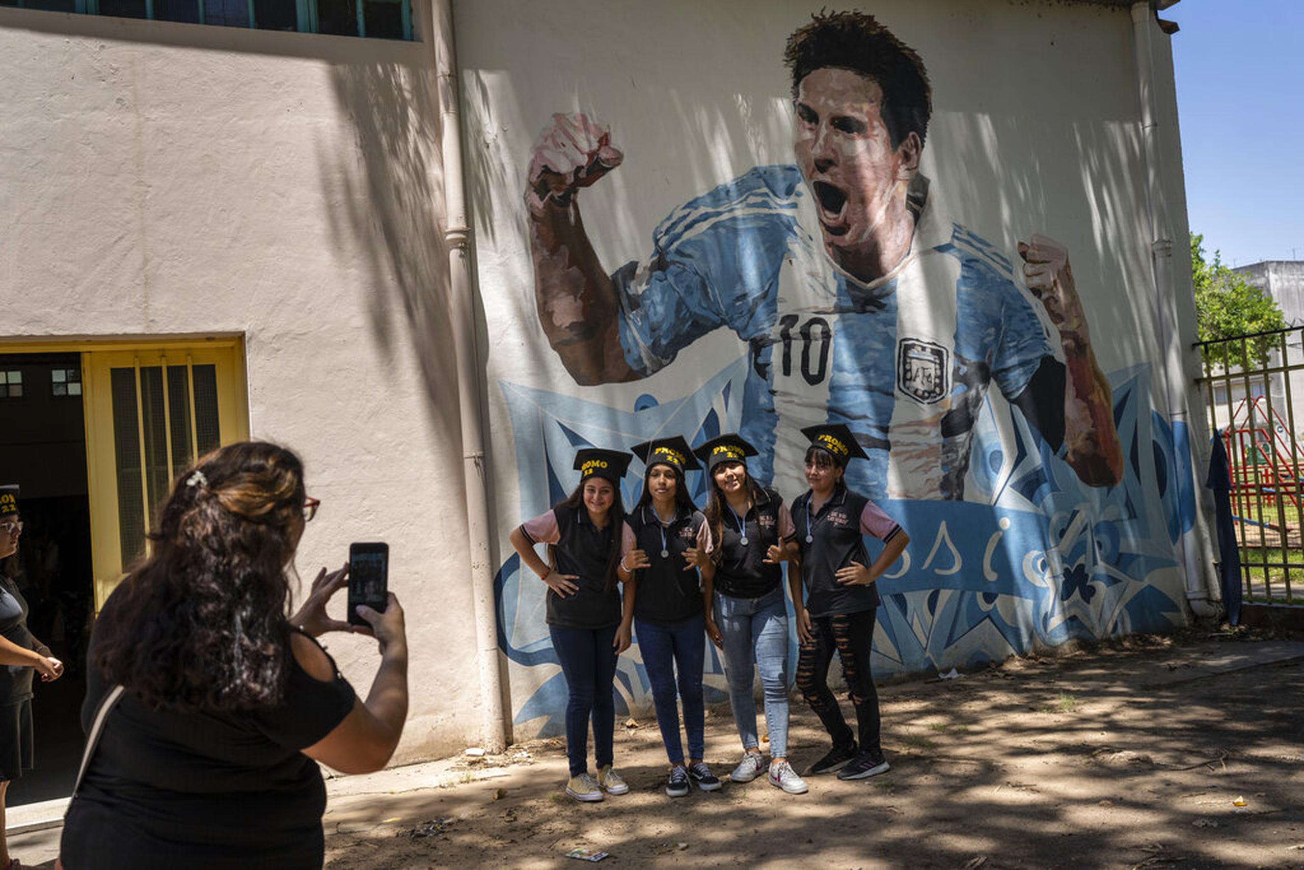 Estudiantes egresados de las escuela primaria General Las Heras, donde Lionel Messi hizo sus estudios, posan para una foto frente a un mural del futbolista, en el último día de clases, en Rosario, Argentina.