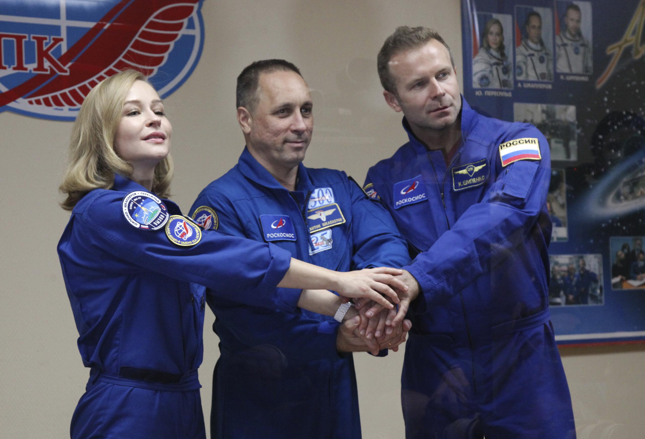 En esta foto proporcionada por Roscosmos, la actriz Yulia Peresild, el director Klim Shipenko y el cosmonauta Anton Shkaplerov, de izquierda a derecha, miembros de la tripulación principal de la nave espacial Soyuz MS-19, posan al final de una conferencia de prensa en las instalaciones de lanzamiento rusas en el cosmódromo de Baikonur, Kazajstán, el lunes 4 de octubre de 2021. (Roscosmos Space Agency vía AP)