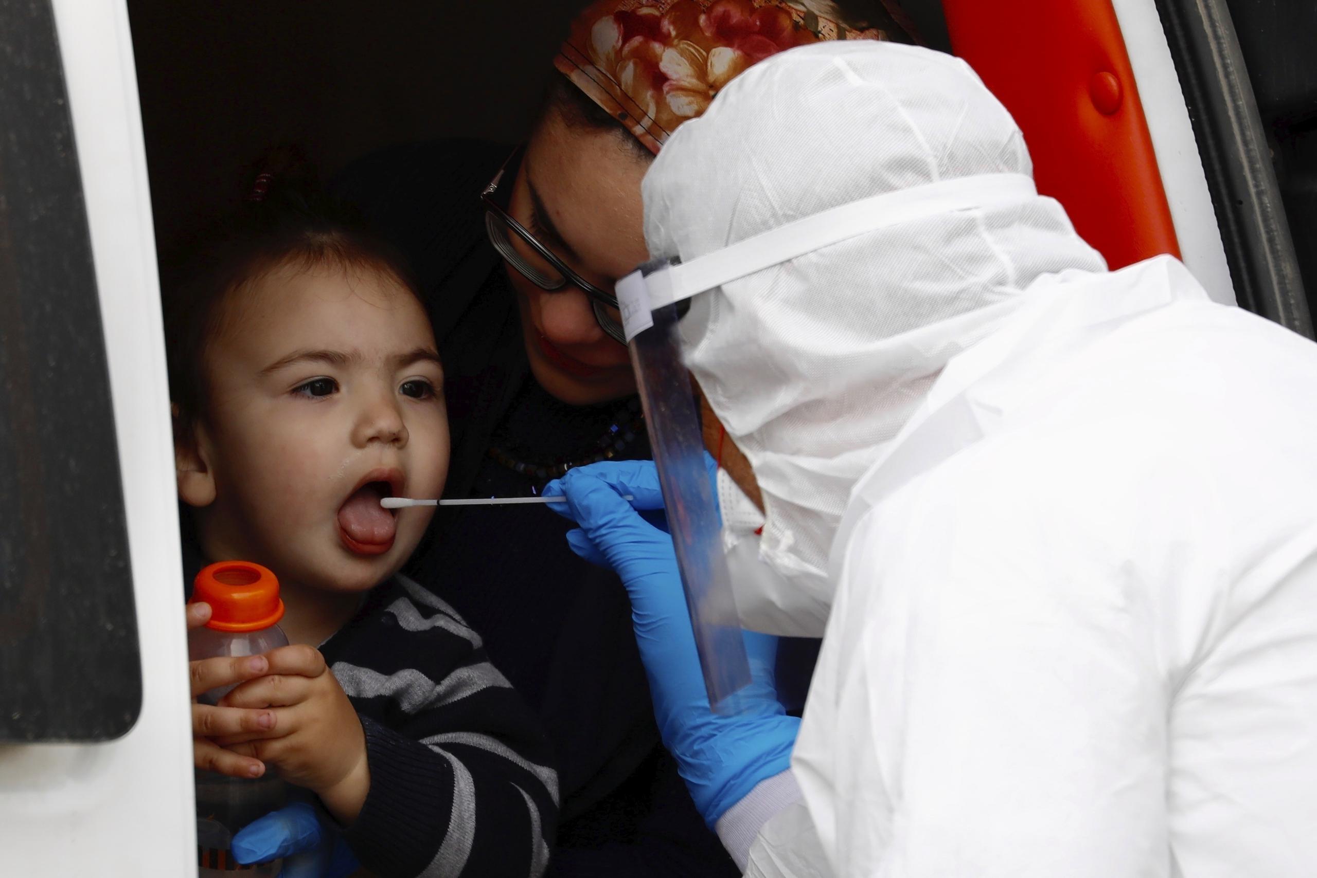 Un trabajador médico con ropa de protección hace una prueba de COVID-19 a un niño.