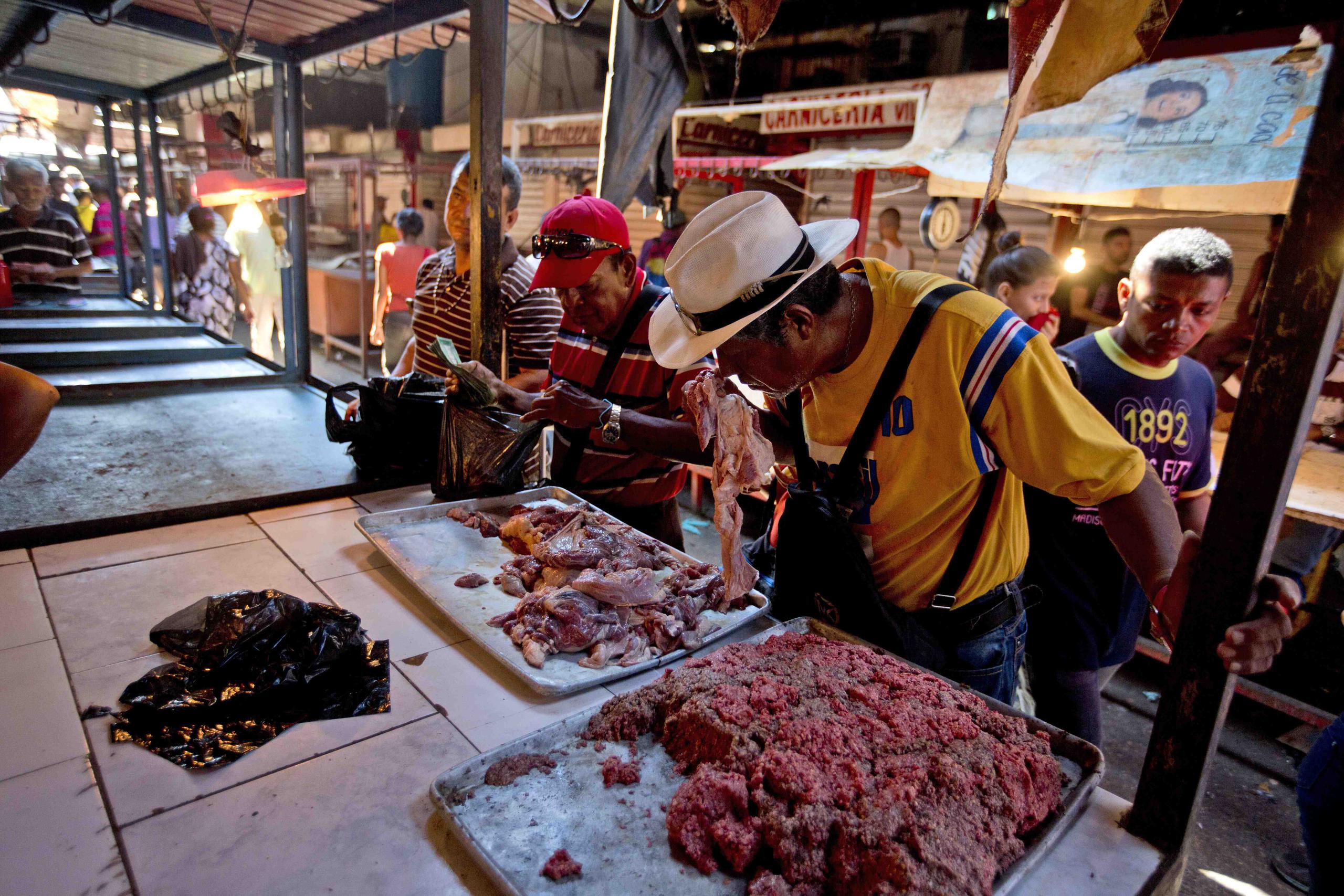 Cliente huele un pedazo de carne dañada en un mercado de Maracaibo, Venezuela. (AP / Fernando Llano)