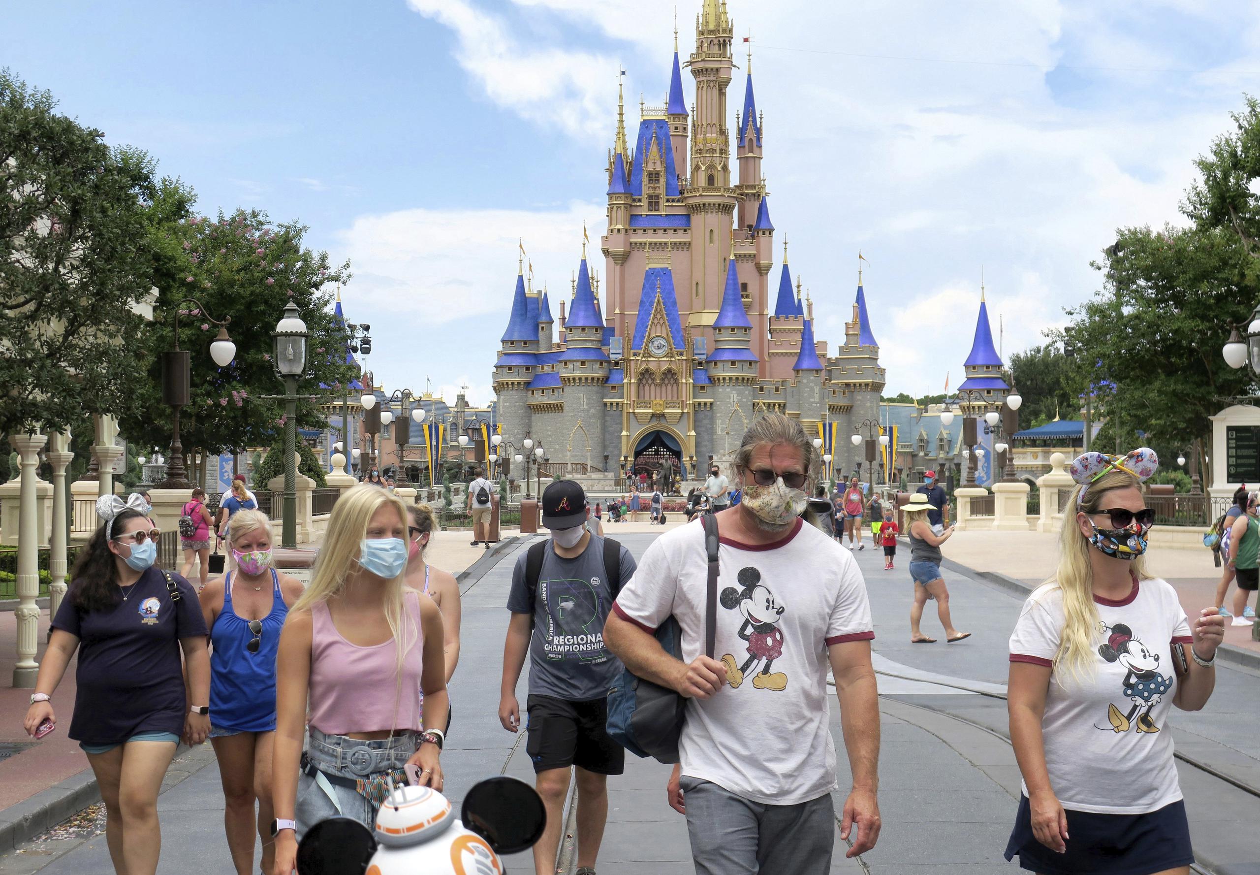 Visitantes utilizan mascarillas en su pasadía en Magic Kingdom, en Walt Disney World en Lake Buena Vista, Florida.