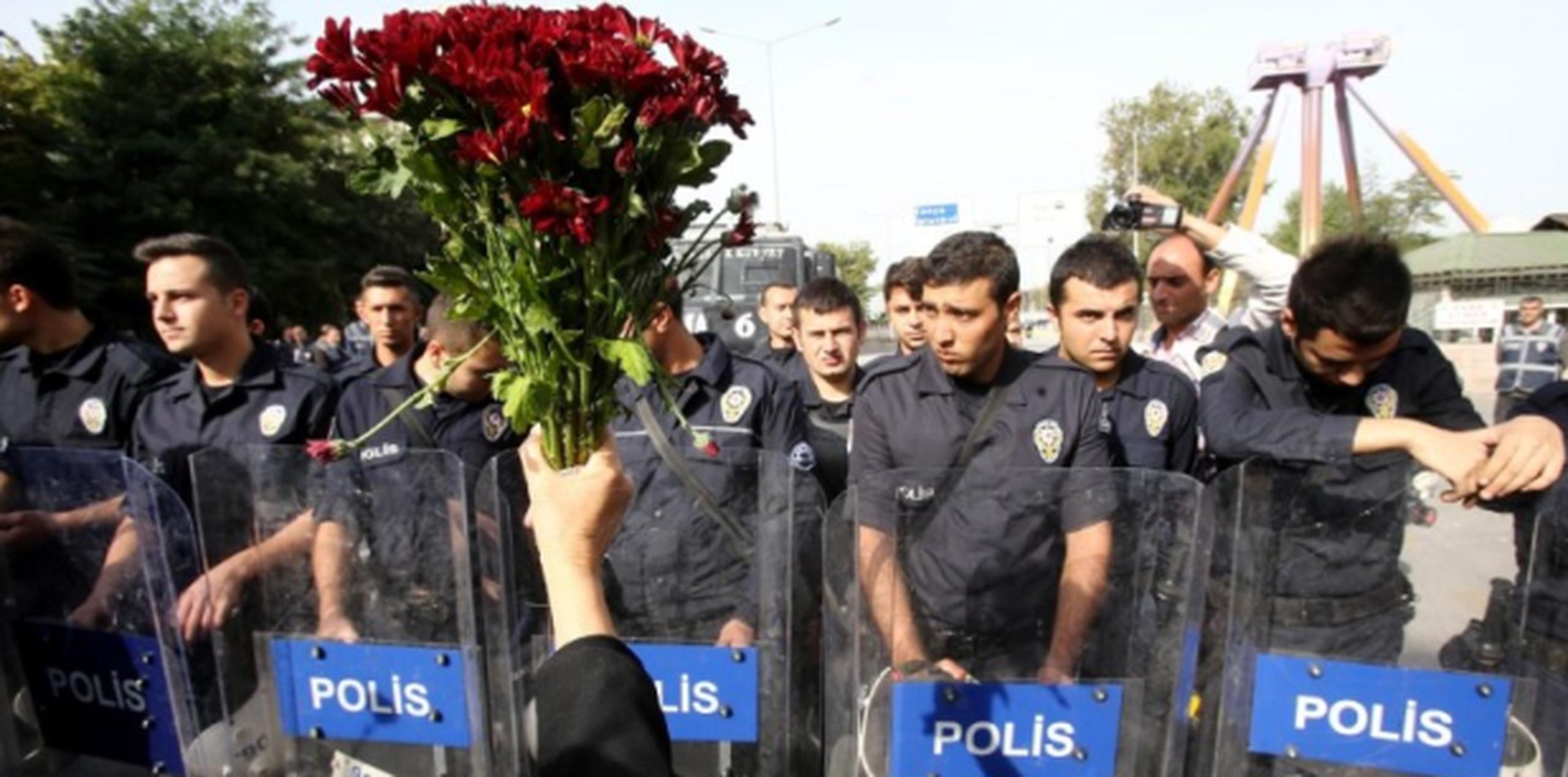 Una manifestante muestra a policías el ramo de claveles que deseaba llevar al área del doble atentado que mató a 95 personas el sábado. (AFP)