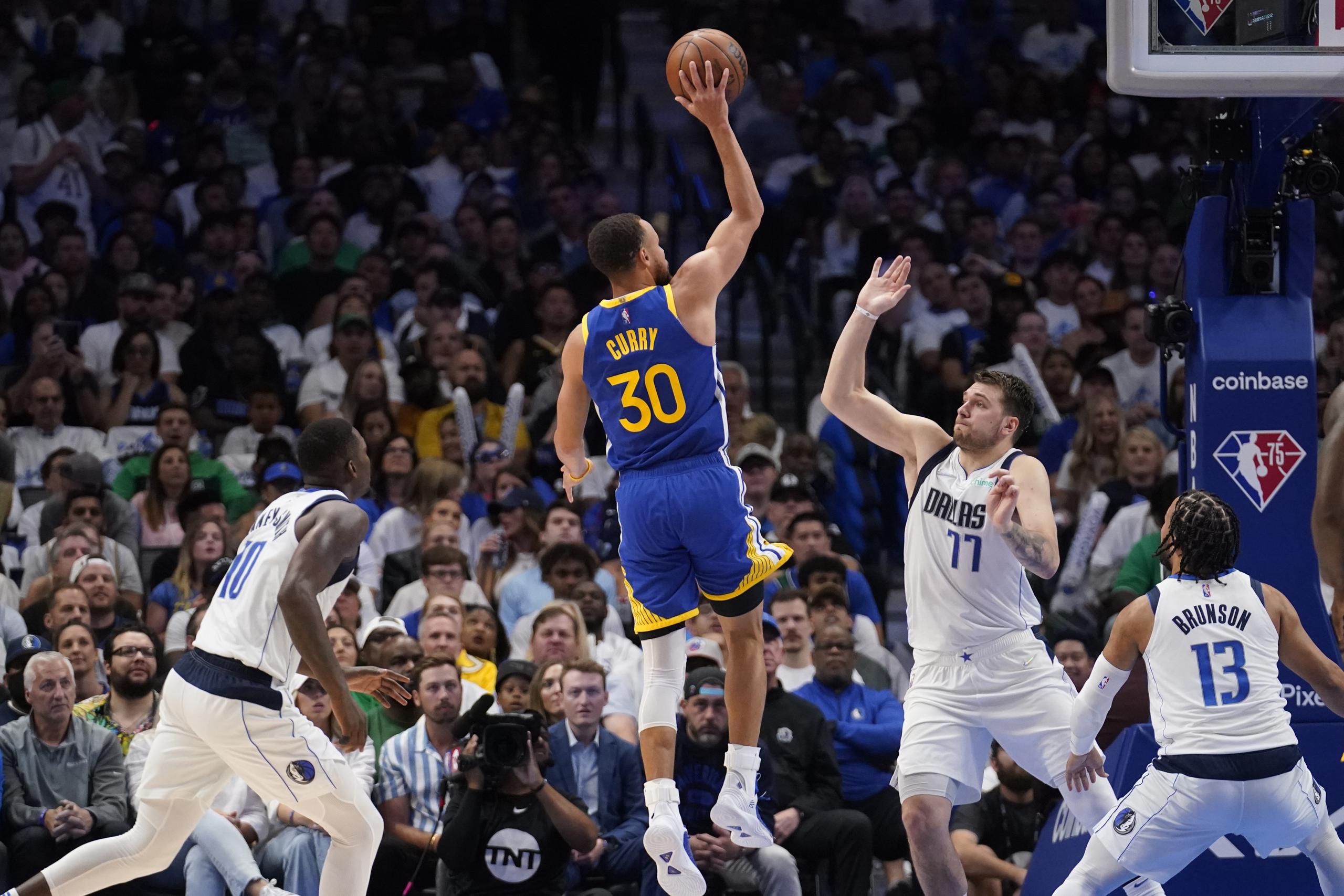 El base de los Warriors de Golden State Stephen Curry lanza el balón superando al base de los Mavericks de Dallas Luka Doncic en el juego 4 de la Final de la Conferencia Oeste.