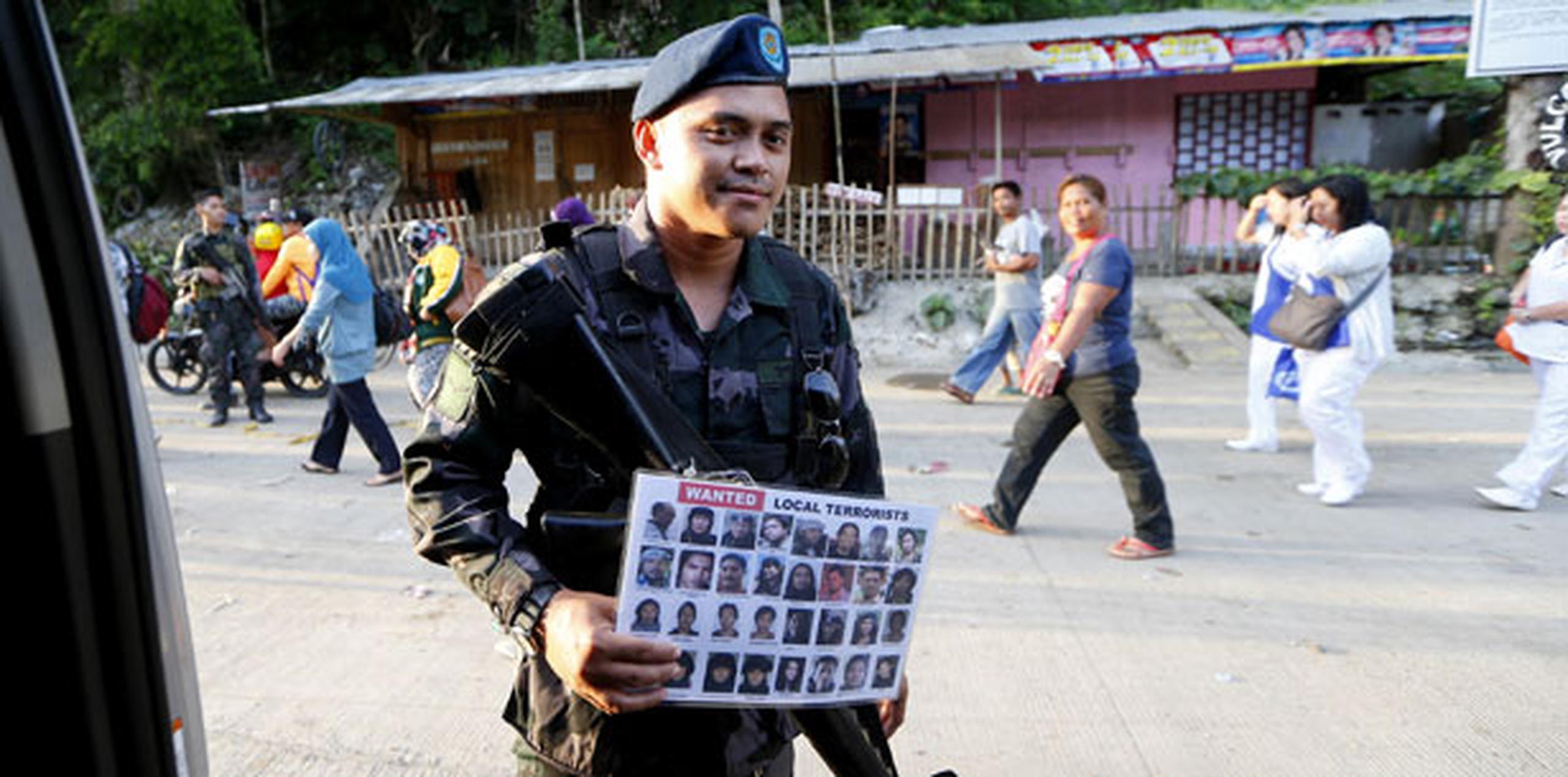 Agente de la policía filipina sostiene cartel con imagen de insurgentes del grupo filipino "Maute". (AP)