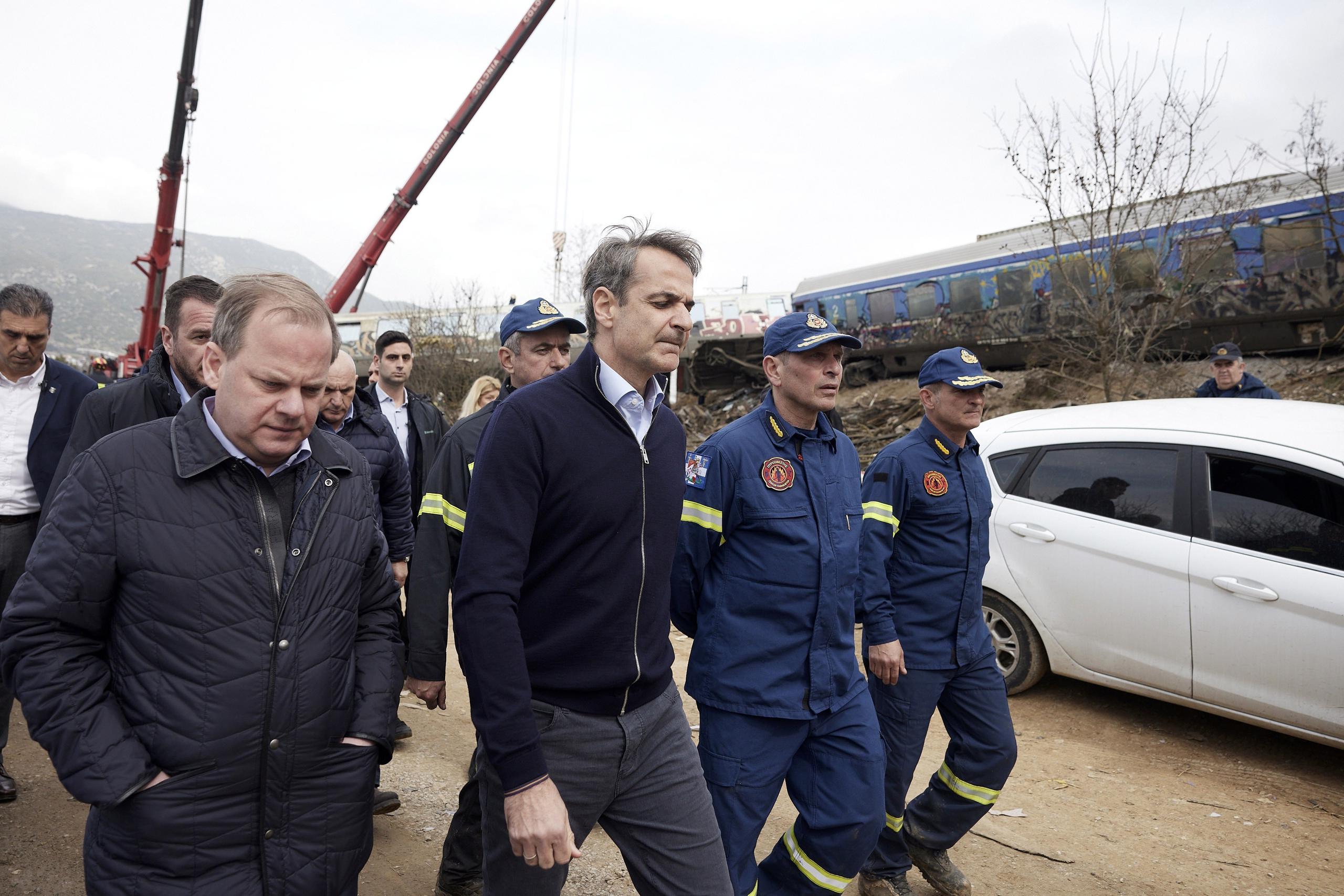 El primer ministro de Grecia, Kyriakos Mitsotakis, en el centro, llegó a la escena con el jefe saliente de transporte, Kostas Karamanlis, a la izquierda, quien presentó su renuncia horas después del incidente que dejó a más de 40 personas muertas.