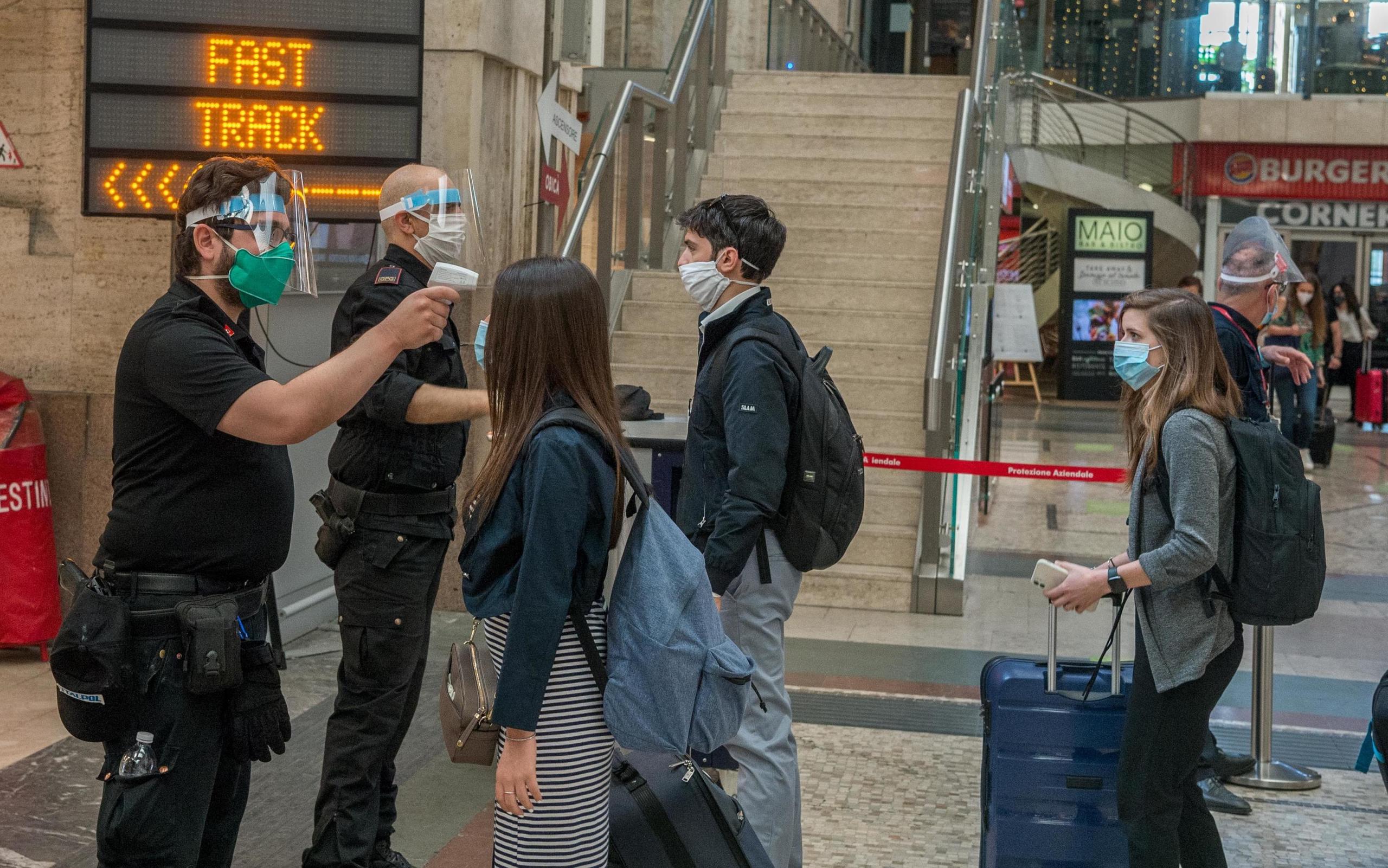 Dos empleados toman la temperatura a los pasajeros en la Estación Centralo de Milán.