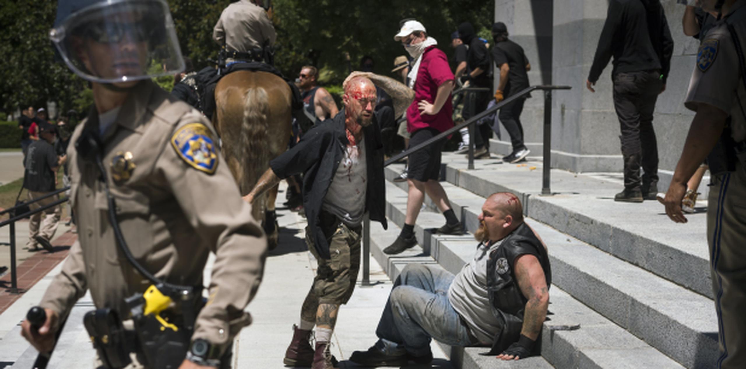 La policía interviene para separar a los grupos que se peleaban frente al capitolio de California. (AP)