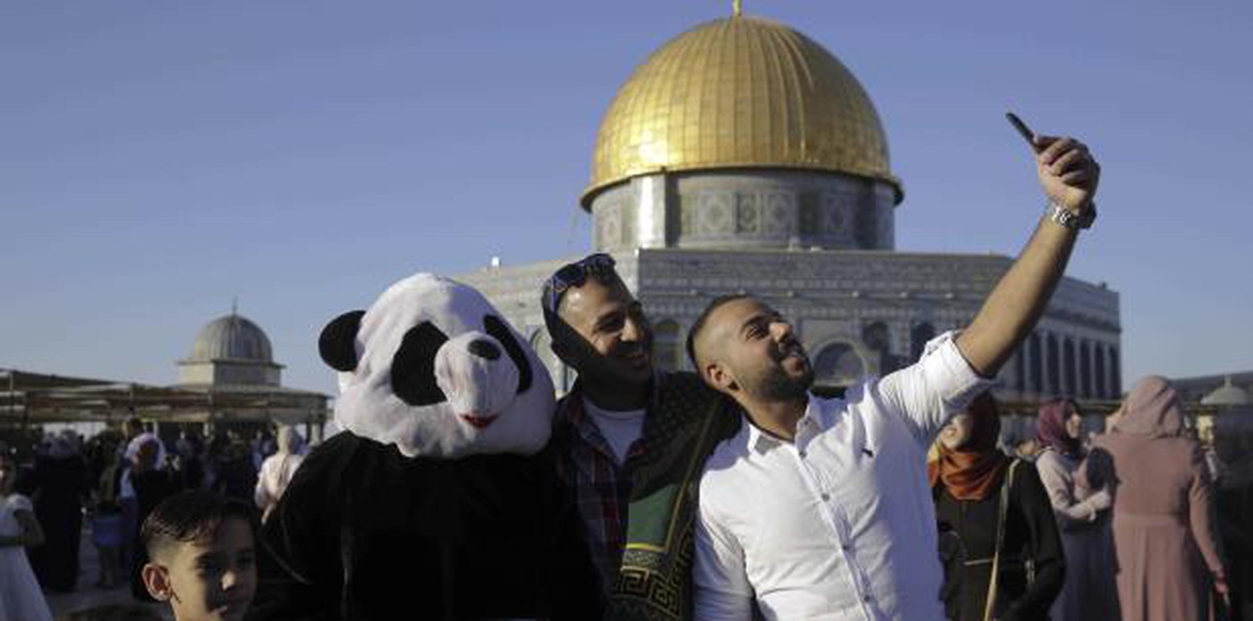 Unos palestinos se toman fotos frente al Domo de la Roca en Israel durante la festividad. (AP)