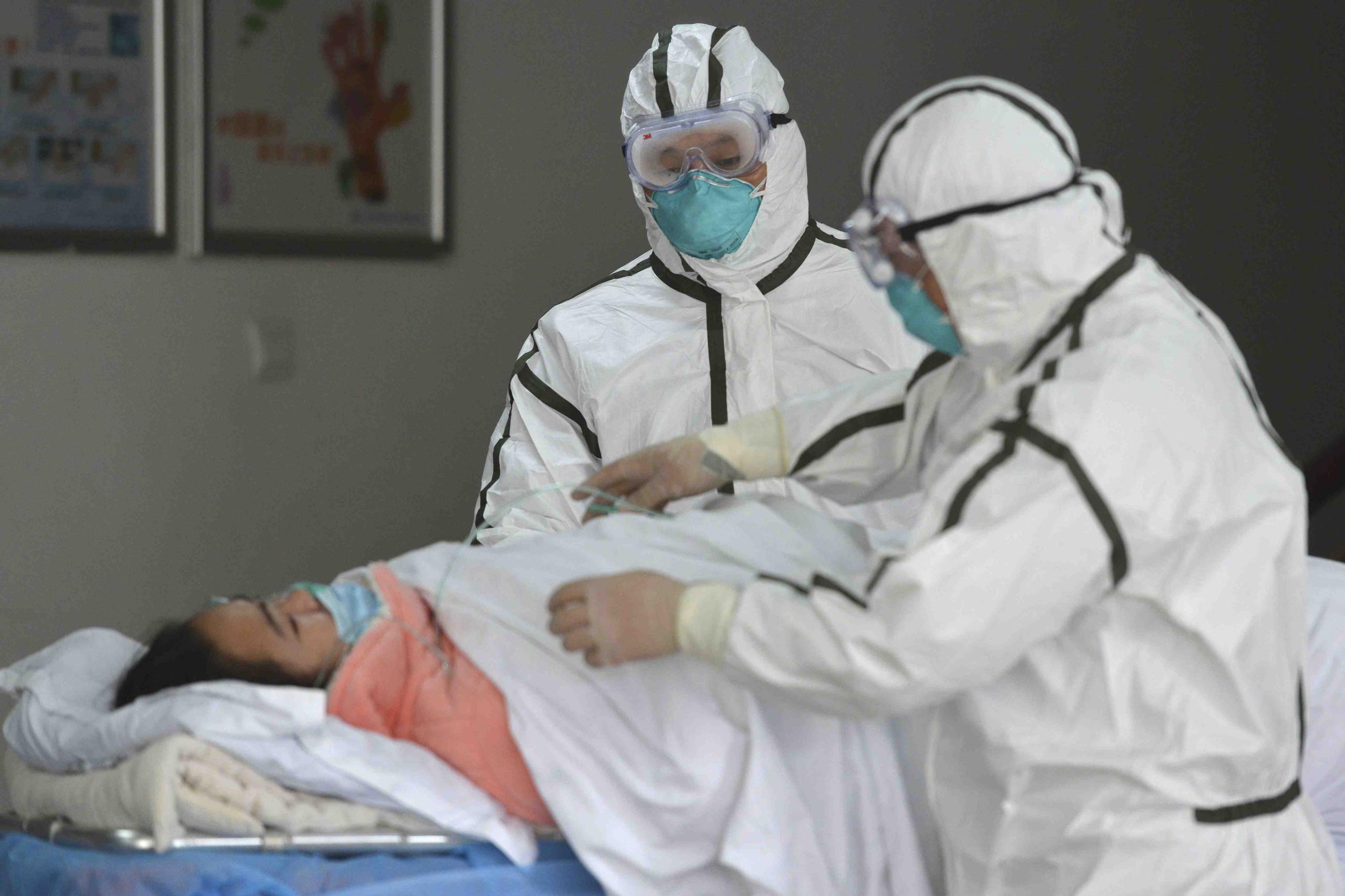 Personal sanitario provisto con trajes protectores traslada a una paciente infectada con coronavirus a un pabellón de aislamiento en el Segundo Hospital del Pueblo en Fuyang, provincia de Anhui, en el centro de China. (Chinatopix vía AP)