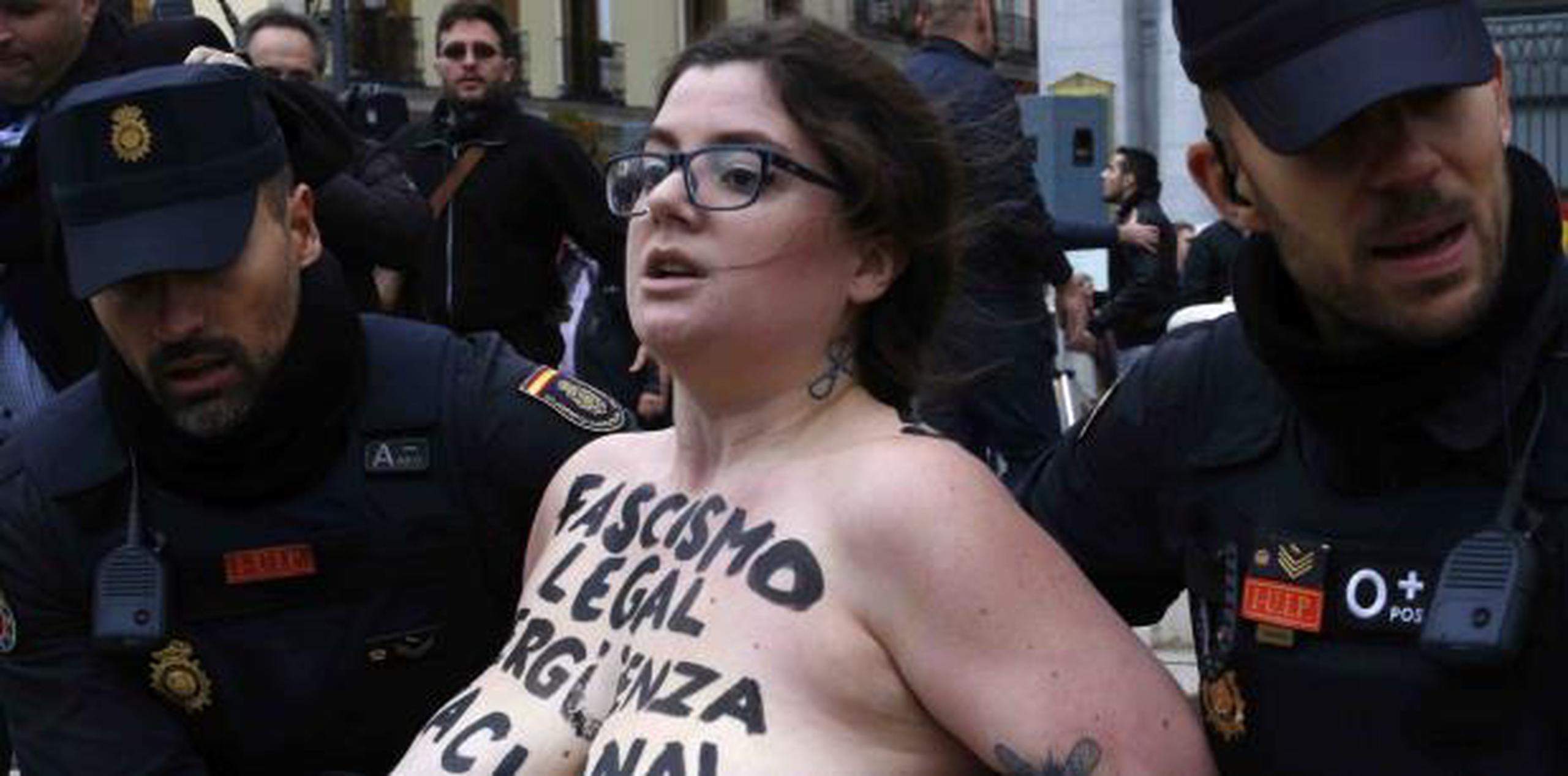 Agentes mantuvieron alejadas de los 200 asistentes al acto a tres miembros del grupo Femen, que irrumpieron con el pecho desnudo y la leyenda “Fascismo legal, vergüenza nacional” pintada en el torso.  (AP)

