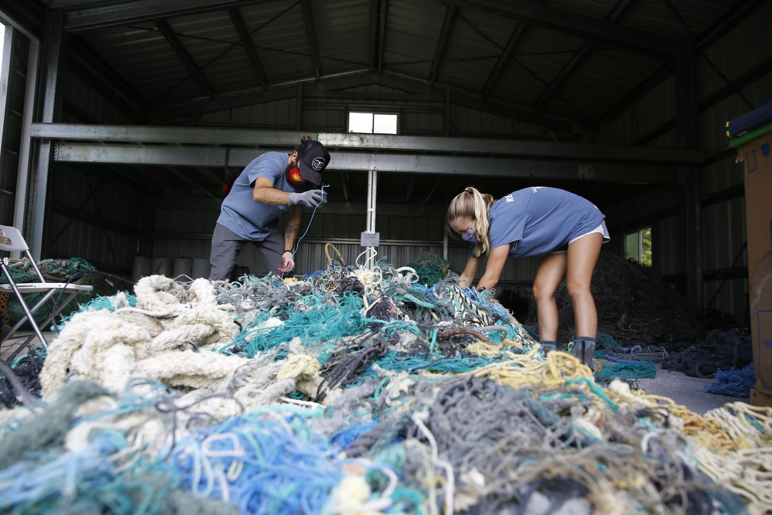 Drew McWhirter (izq) y Raquel Corniuk tratan de desenredar una enorme medeja de redes de pescadores en el Centro de Investigación de Desechos Marinos de la Universidad del Pacífico de Hawái en Kaneohe, Hawái.