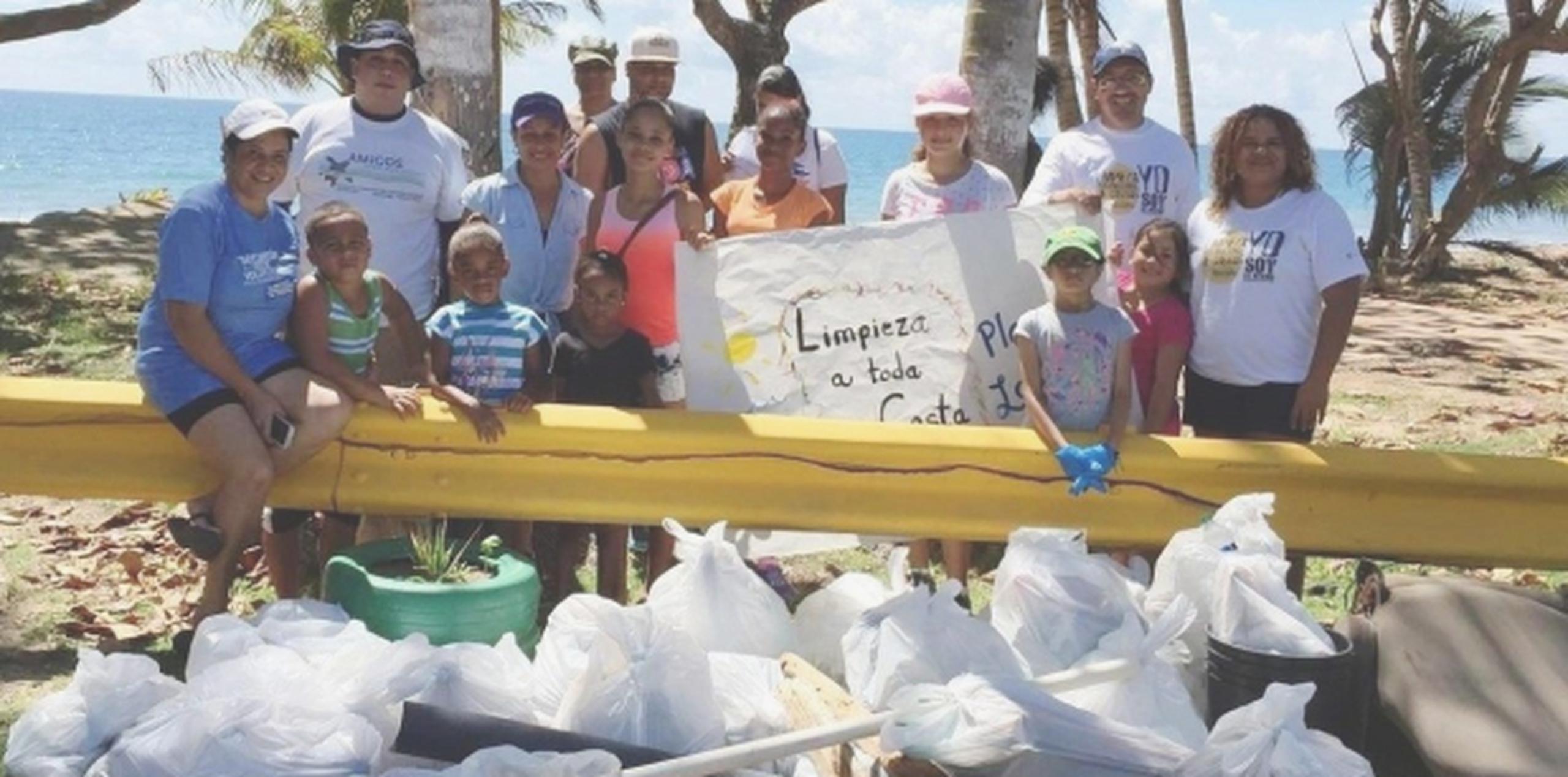 Parte de los niños y los voluntarios participantes de la iniciativa ambiental muestran algo de la basura que fue recogida en la playa Los Pinos de Maunabo. (Suministrada)